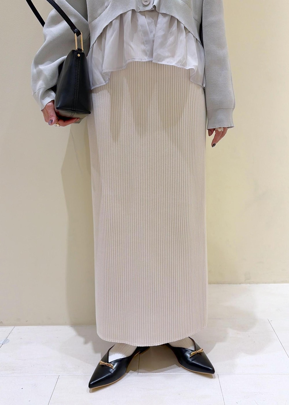 ブラック系のショルダーバッグ、ブラック系のパンプス、ホワイト系のスカートを着用したレディースの春コーディネートの7枚目の写真