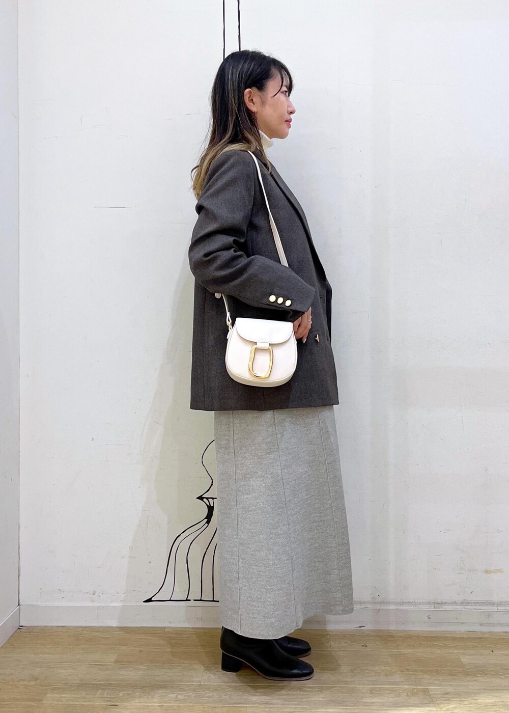 ホワイト系のショルダーバッグ、ブラック系のブーツ、ホワイト系のニット/セーターを着用したレディースの冬コーディネートの4枚目の写真