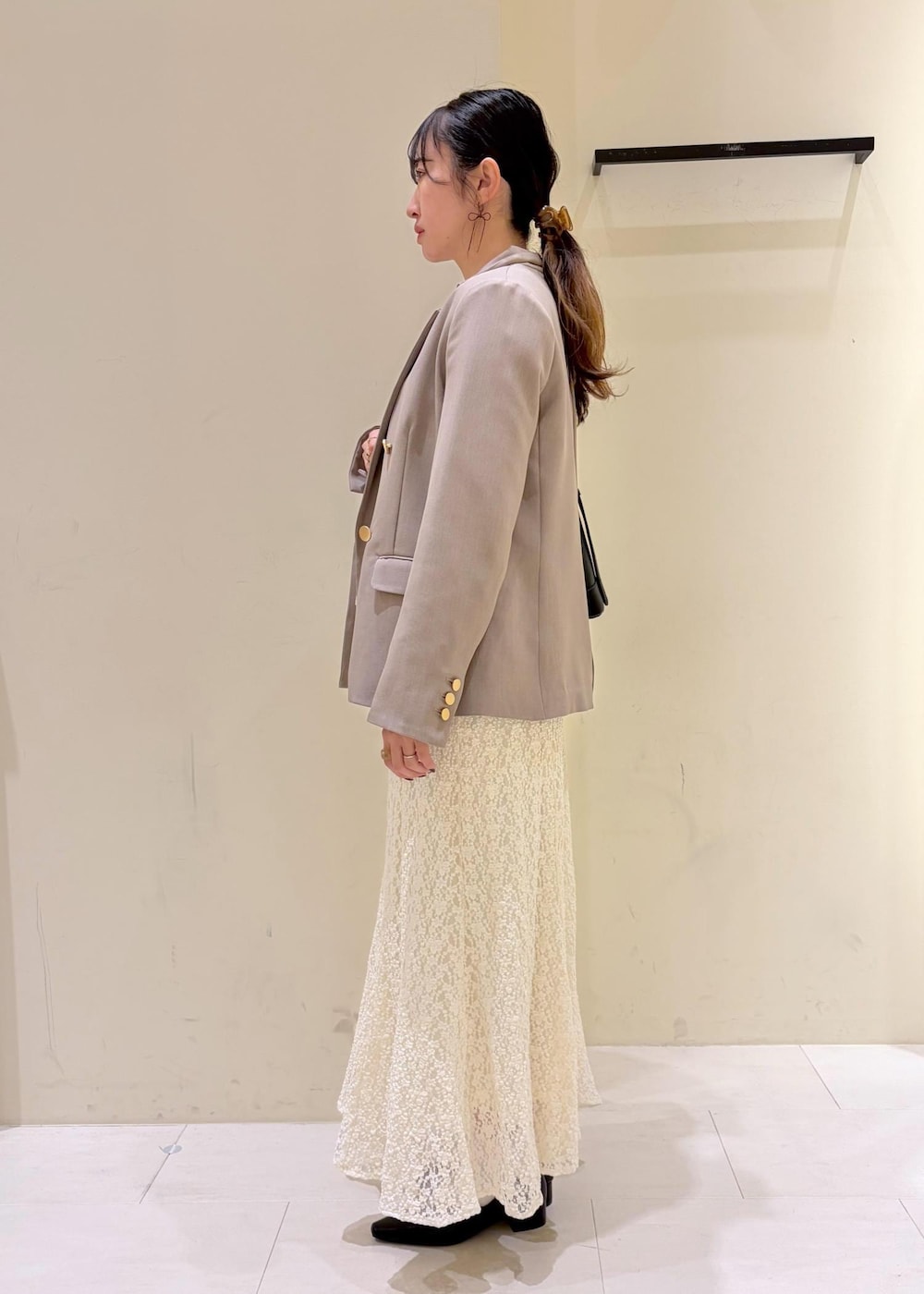 ブラック系のショルダーバッグ、ホワイト系のスカート、ホワイト系のカーディガン/ボレロを着用したレディースの冬コーディネートの4枚目の写真