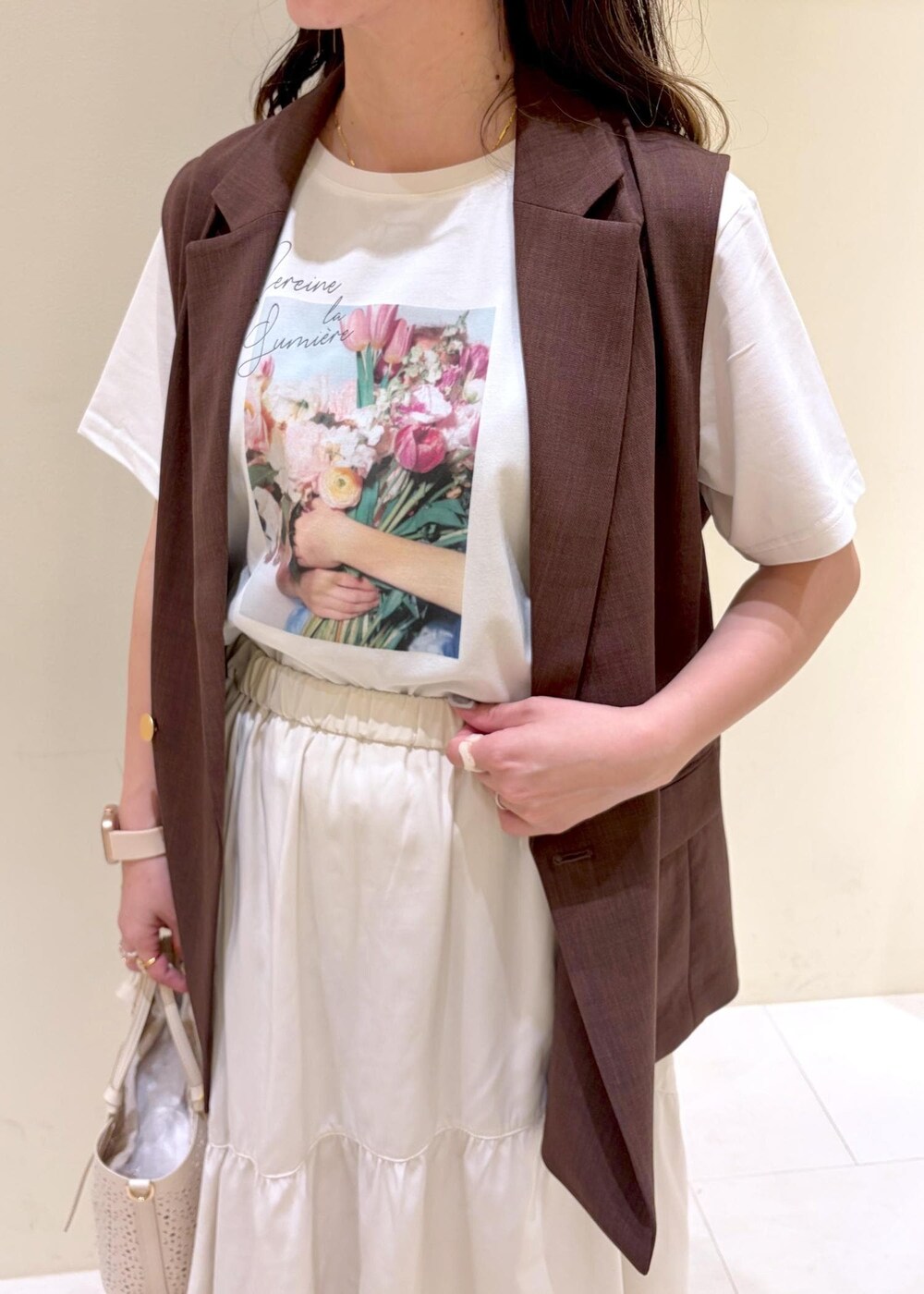 ホワイト系のスカート、ホワイト系のTシャツ/カットソー、ブラウン系のベストを着用したレディースの春コーディネートの5枚目の写真