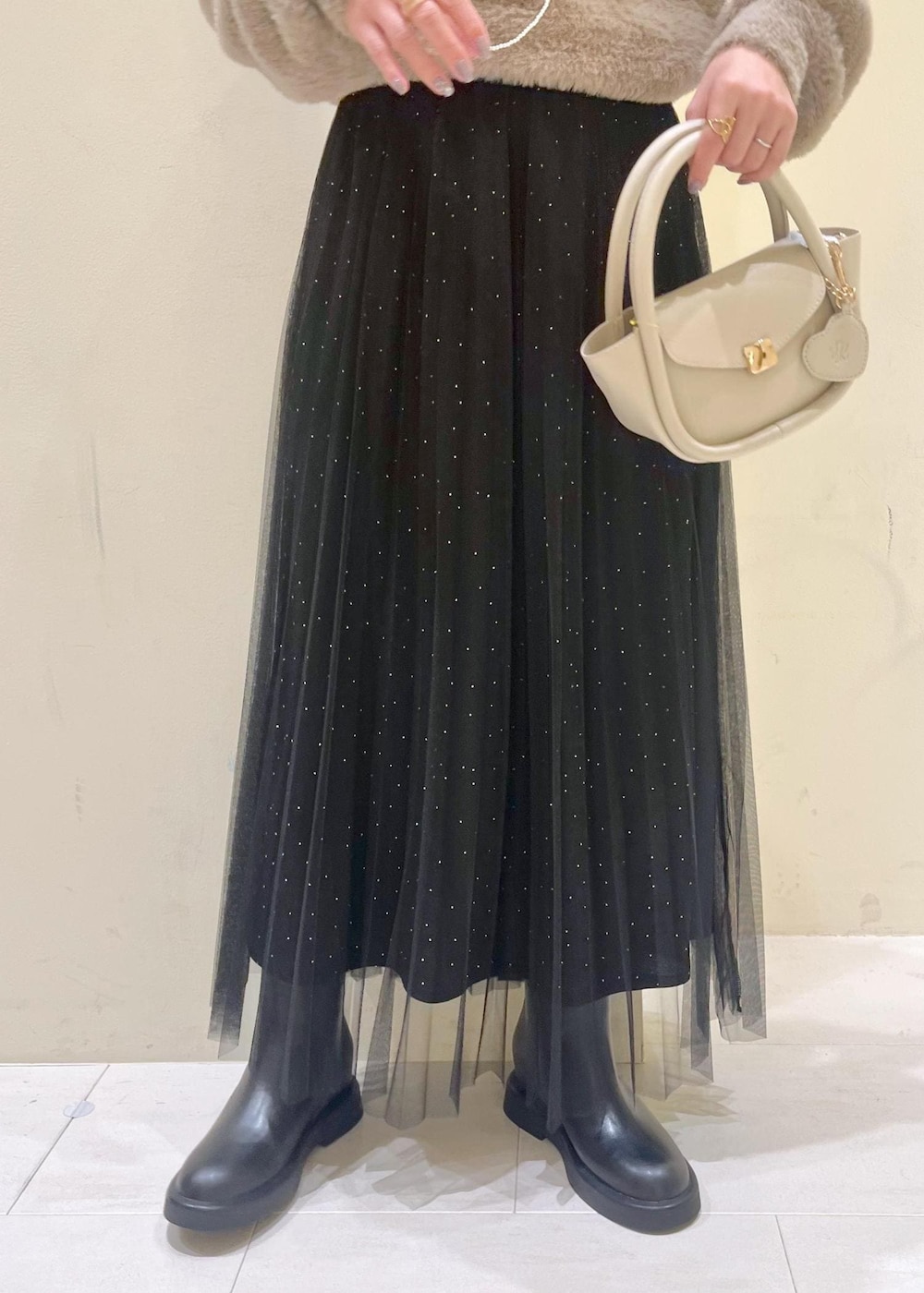 ホワイト系のショルダーバッグ、ブラック系のブーツ、ブラック系のスカートを着用したレディースの冬コーディネートの7枚目の写真
