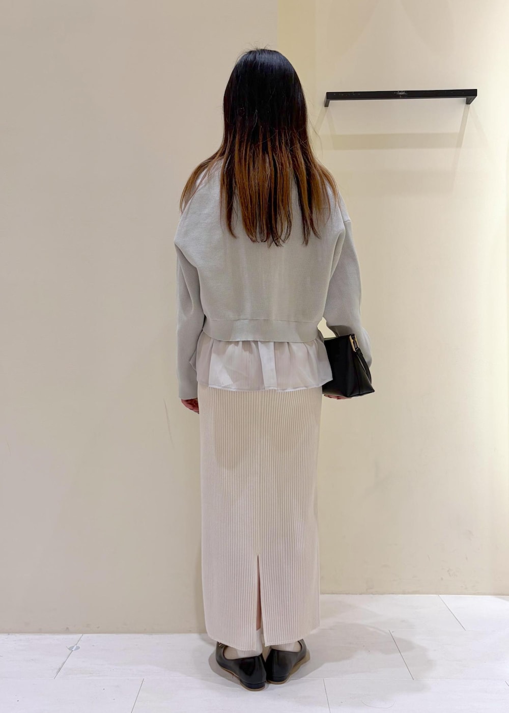 ブラック系のショルダーバッグ、ブラック系のパンプス、ホワイト系のスカートを着用したレディースの春コーディネートの3枚目の写真