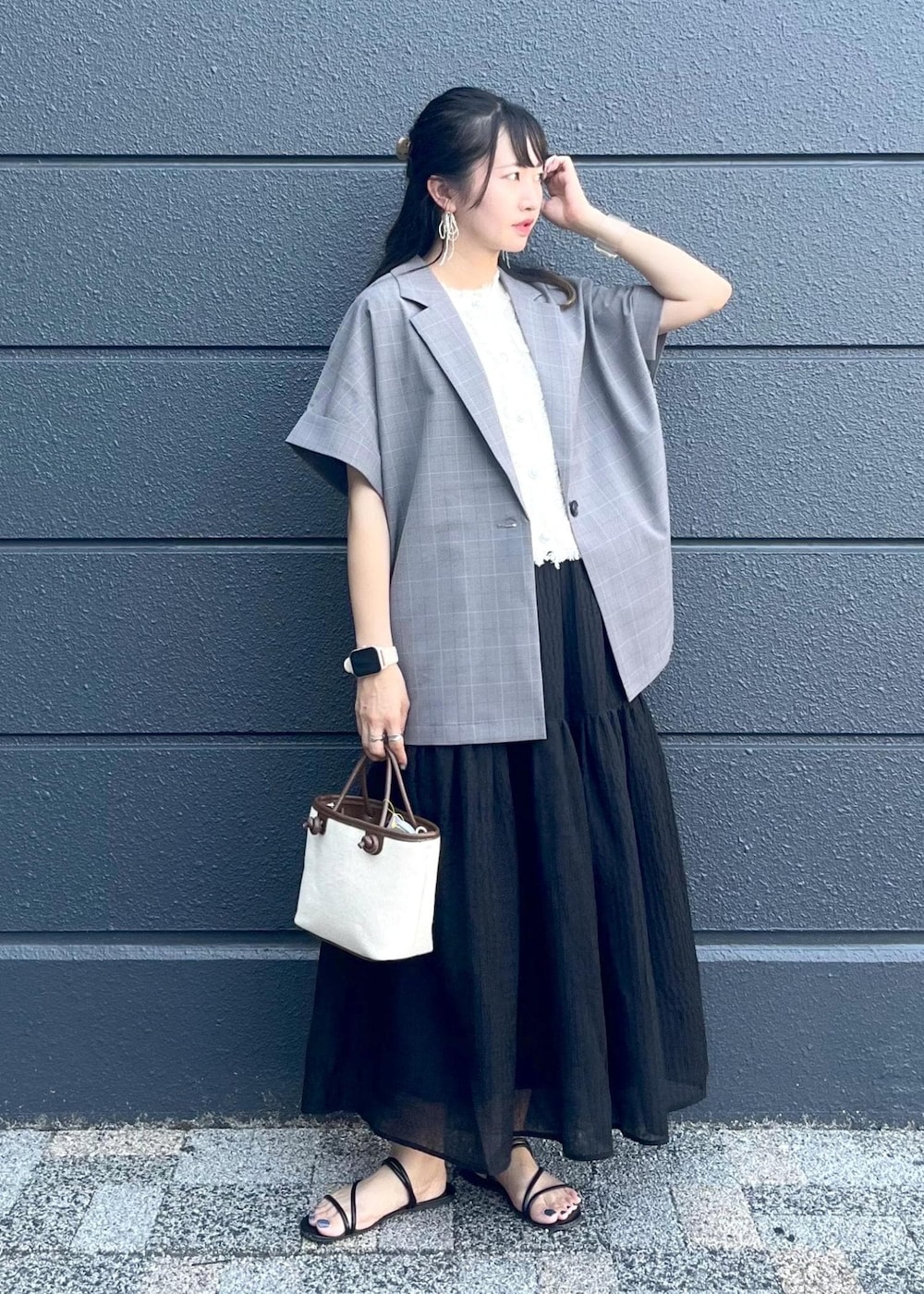グレー系のテーラードジャケット、ブラウン系のトートバッグ、ブラック系のスカートを着用したレディースの夏コーディネートの9枚目の写真