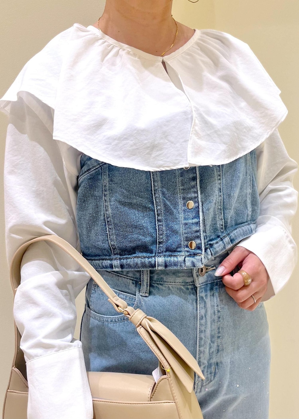 ベージュ系のハンドバッグ、ブルー系のデニムパンツ、ブルー系のベストを着用したレディースの春コーディネートの5枚目の写真