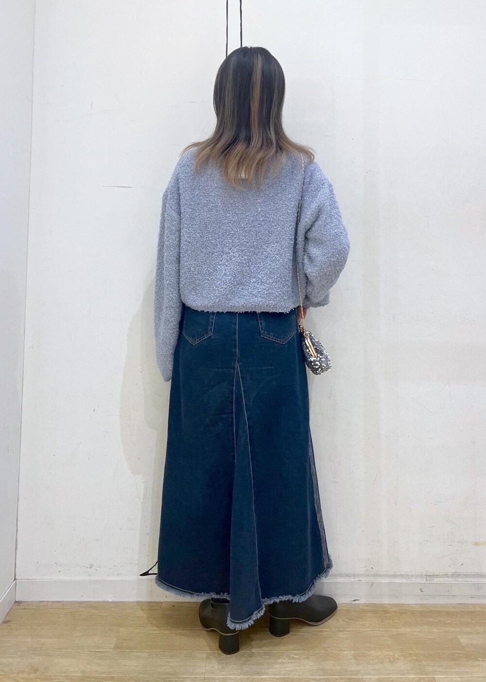 ブラック系のブーツ、グレー系のショルダーバッグ、ブルー系のデニムスカートを着用したレディースの冬コーディネートの5枚目の写真