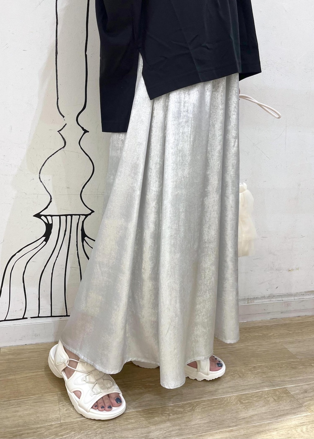 シルバー系のスカート、ブラック系のTシャツ/カットソー、ホワイト系のサンダルを着用したレディースの夏コーディネートの7枚目の写真