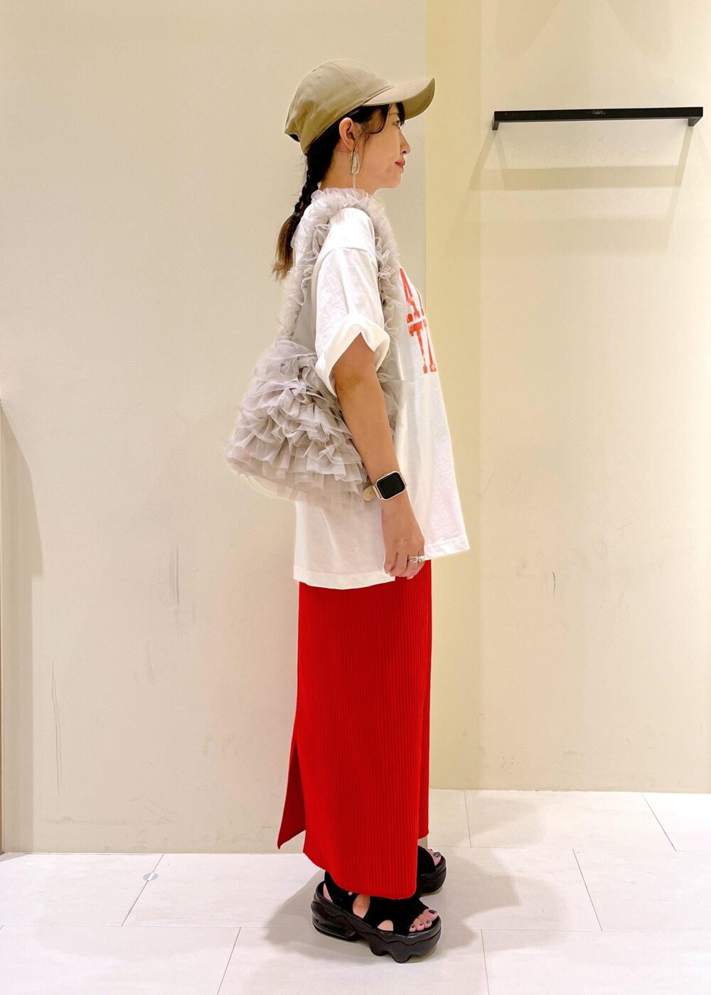 オレンジ系のスカート、ベージュ系のショルダーバッグ、ホワイト系のTシャツ/カットソーを着用したレディースの夏コーディネートの4枚目の写真