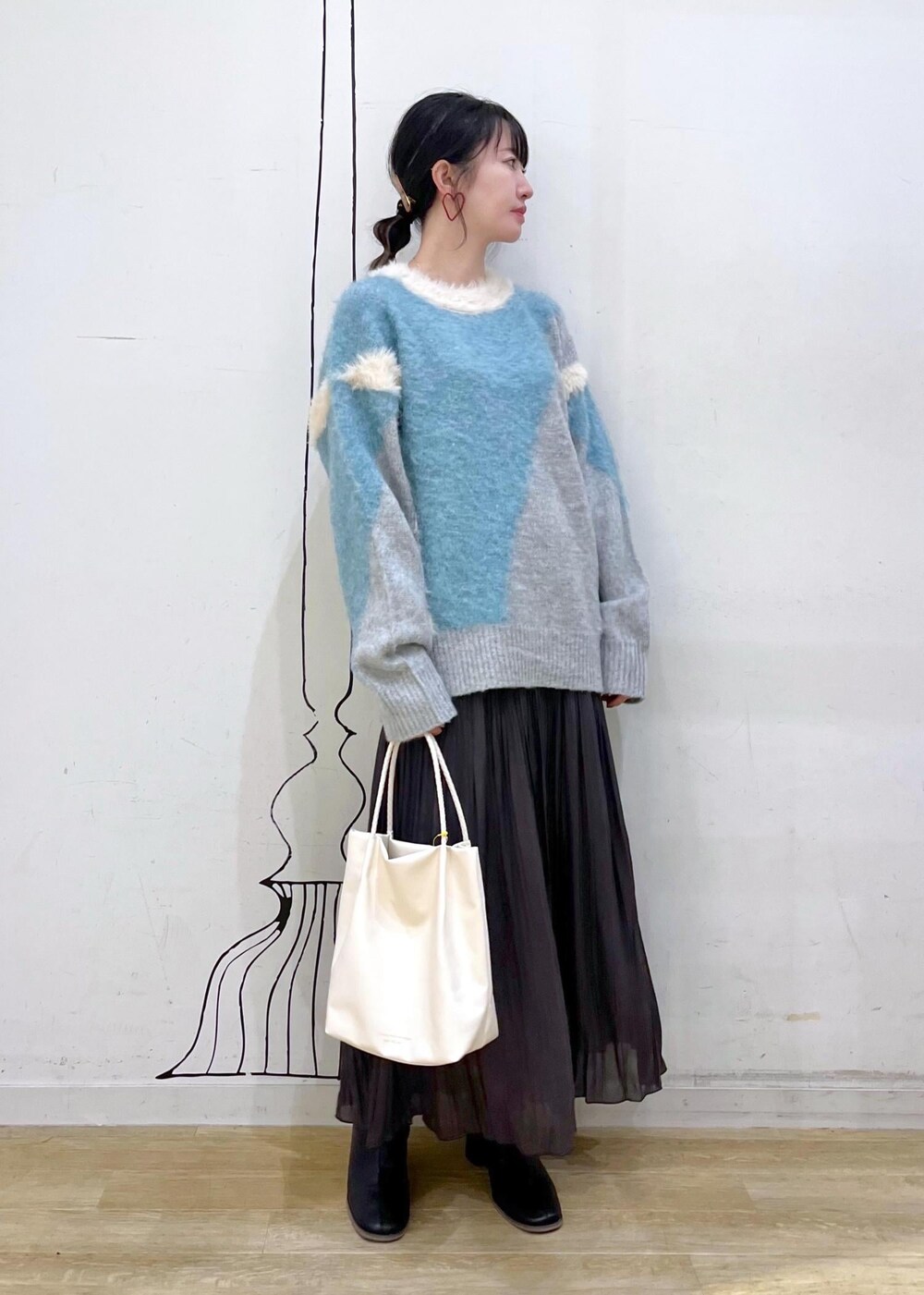 ブラック系のブーツ、ブルー系のニット/セーター、ブラウン系のスカートを着用したレディースの秋コーディネートの2枚目の写真