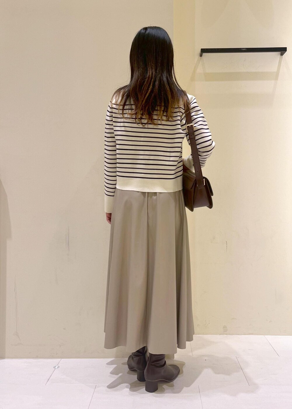 レッド系のショルダーバッグ、ベージュ系のスカート、ホワイト系のカーディガン/ボレロを着用したレディースの秋コーディネートの4枚目の写真