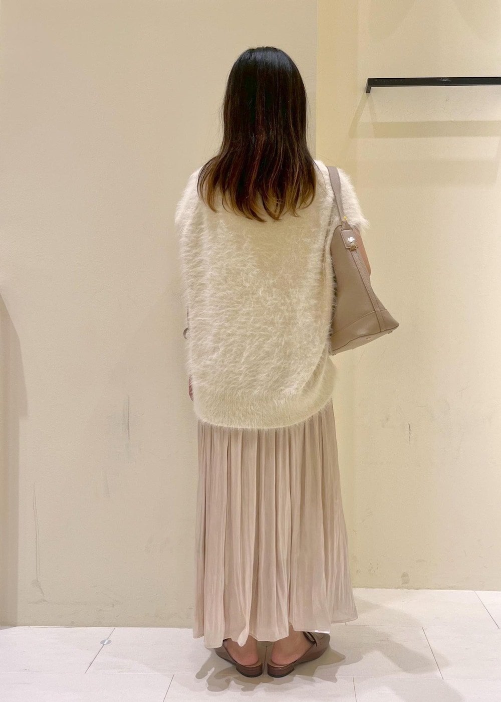 イエロー系のローファー、ベージュ系のスカート、ベージュ系のショルダーバッグを着用したレディースの夏コーディネートの4枚目の写真