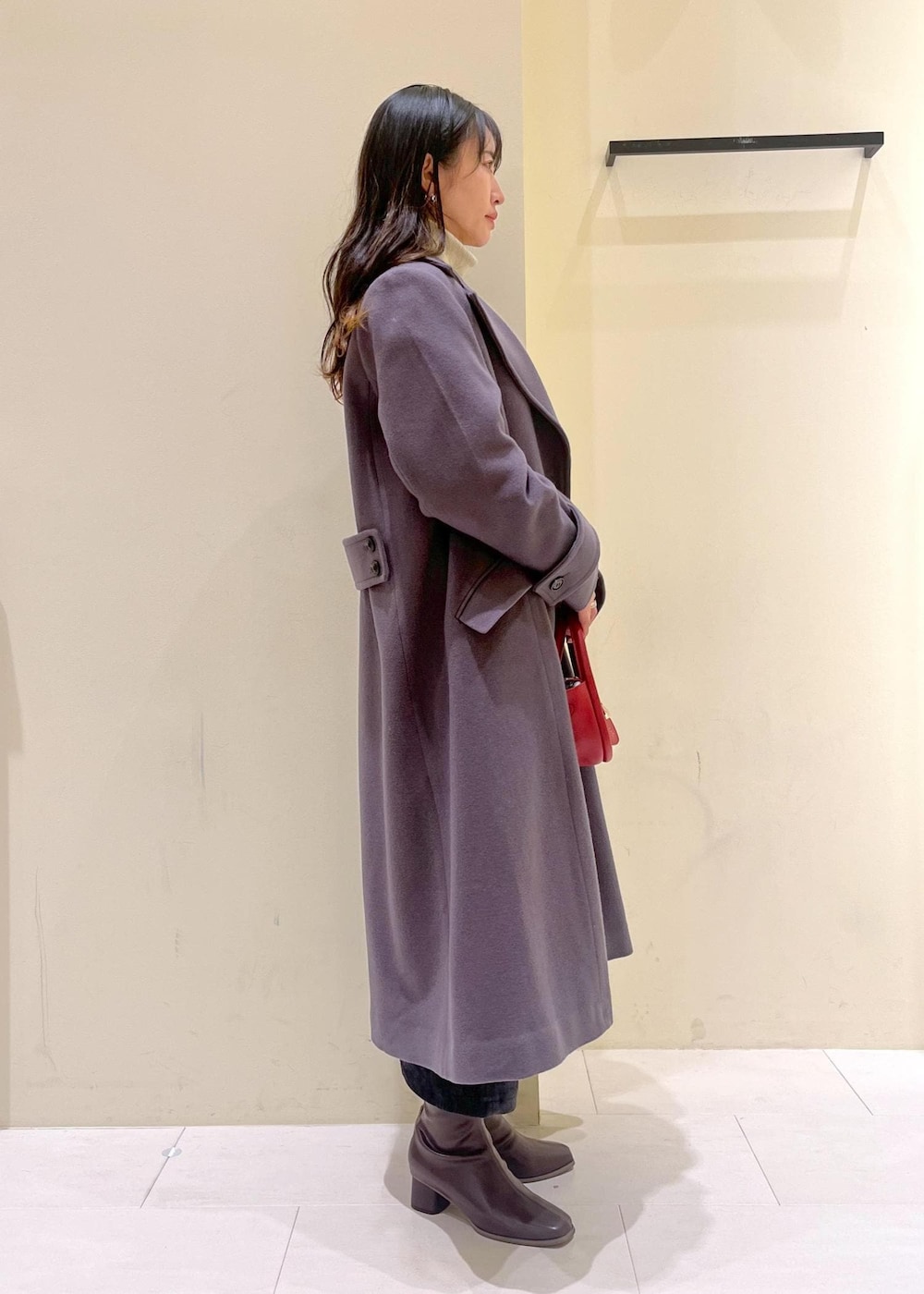 ホワイト系のニット/セーター、グレー系のチェスターコート、レッド系のショルダーバッグを着用したレディースの冬コーディネートの3枚目の写真