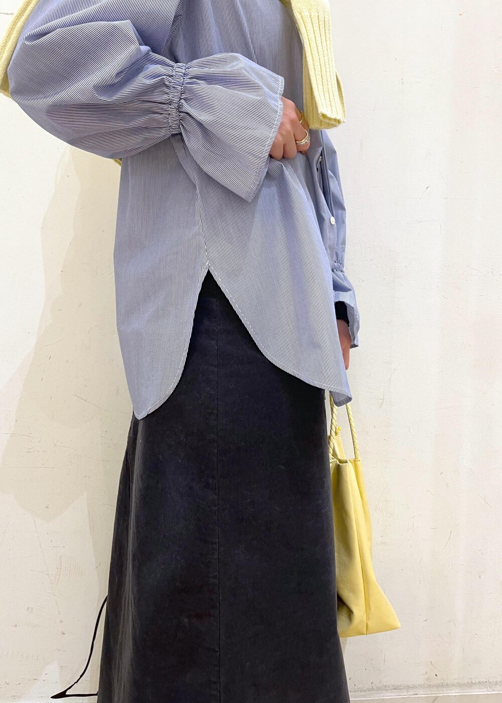 イエロー系のトートバッグ、グレー系のスカート、ブルー系のシャツ/ブラウスを着用したレディースの冬コーディネートの5枚目の写真