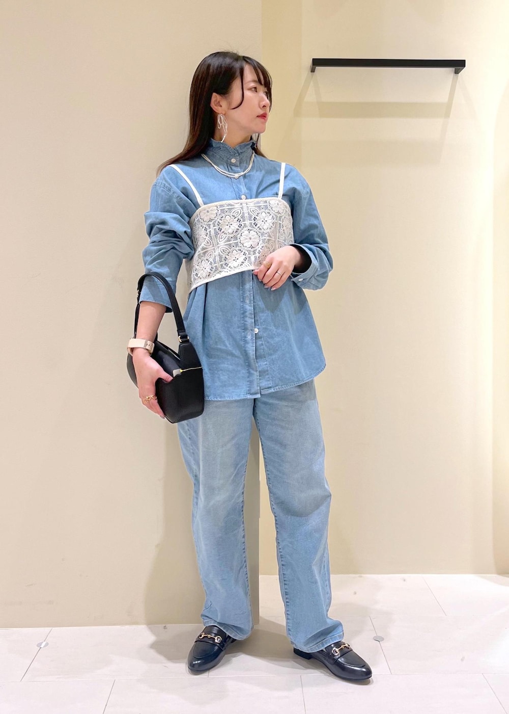 ブルー系のデニムパンツ、ホワイト系のキャミソール、ブラック系のハンドバッグを着用したレディースの春コーディネートの2枚目の写真