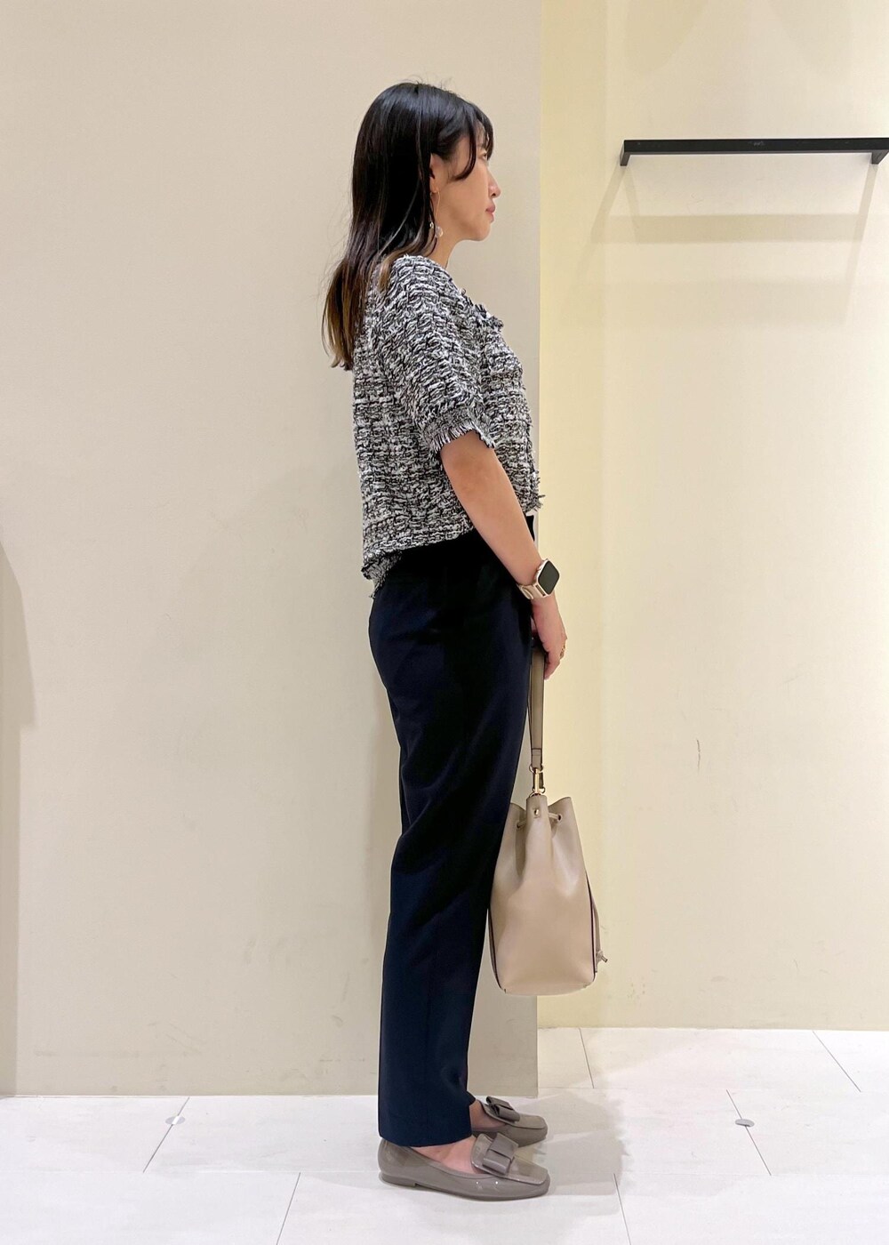 ブルー系のスラックス、ベージュ系のショルダーバッグ、ブラック系のカーディガン/ボレロを着用したレディースの夏コーディネートの3枚目の写真