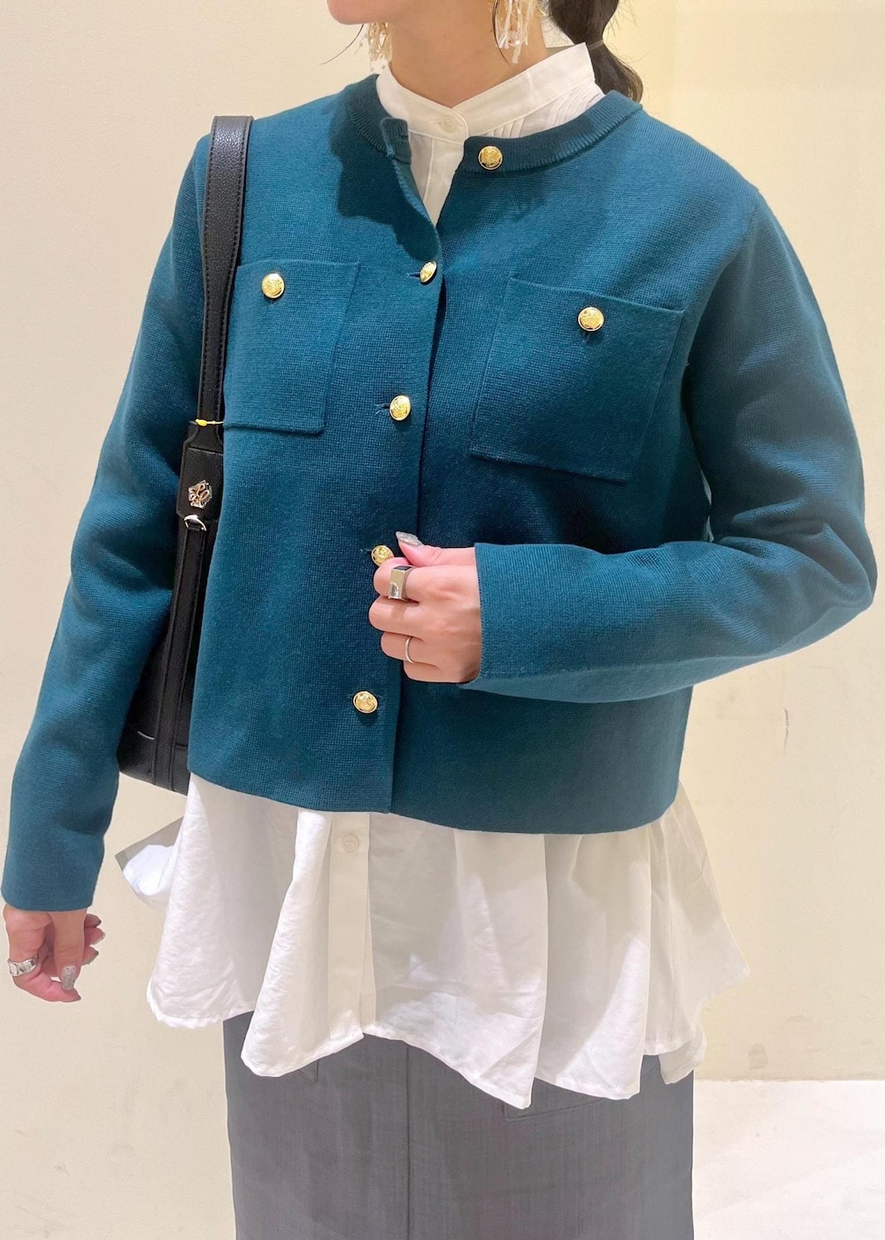 グレー系のスカート、ホワイト系のシャツ/ブラウス、グリーン系のカーディガン/ボレロを着用したレディースの秋コーディネートの5枚目の写真