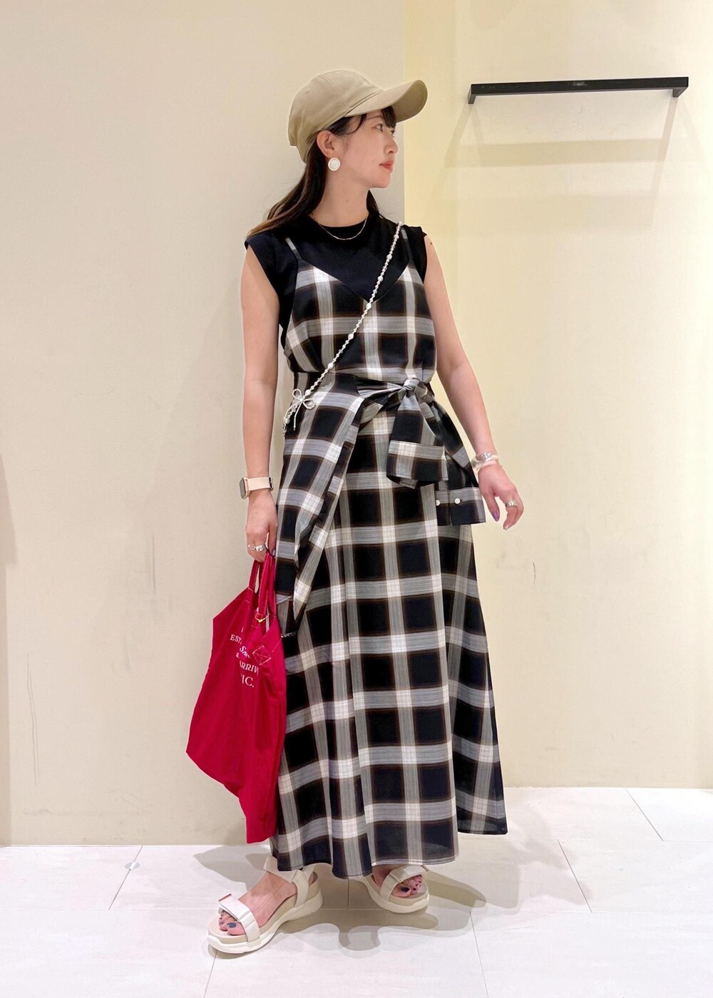 ブラック系のニット/セーター、ホワイト系のサンダル、レッド系のトートバッグを着用したレディースの夏コーディネートの2枚目の写真