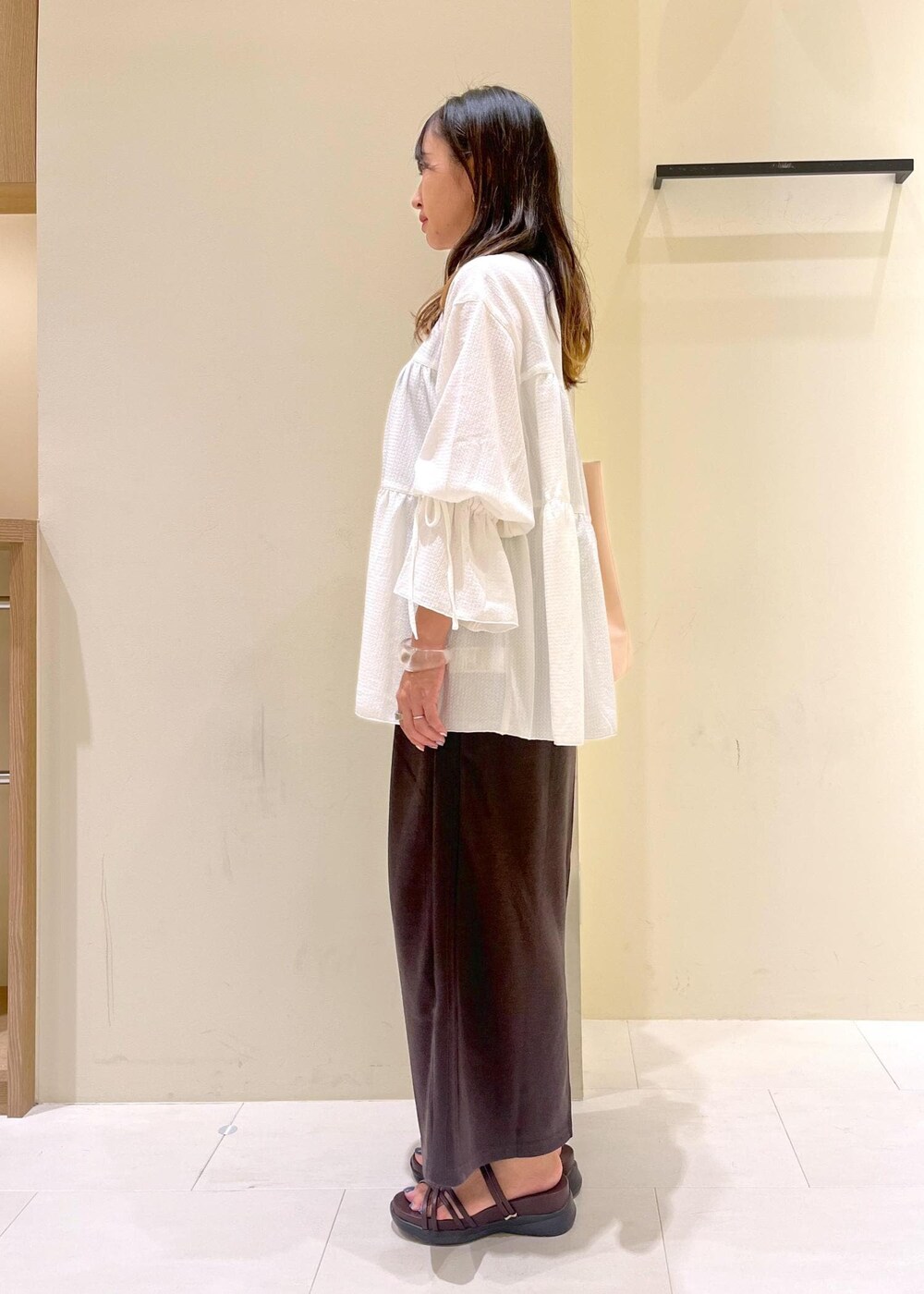 ピンク系のトートバッグ、ブラウン系のサンダル、ホワイト系のシャツ/ブラウスを着用したレディースの夏コーディネートの4枚目の写真