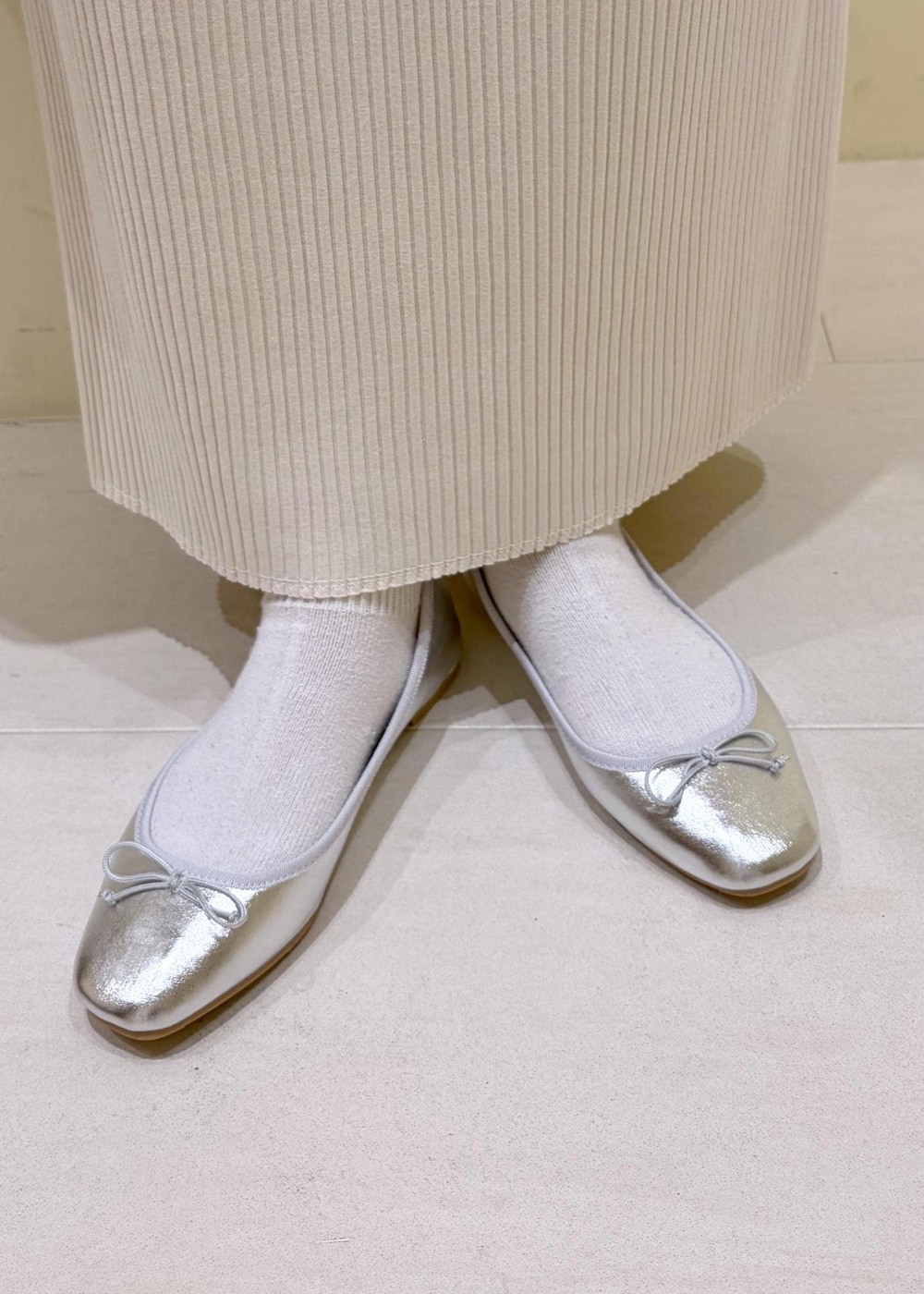 シルバー系のバレエシューズ、ホワイト系のシャツ/ブラウス、イエロー系のニット/セーターを着用したレディースの冬コーディネートの10枚目の写真