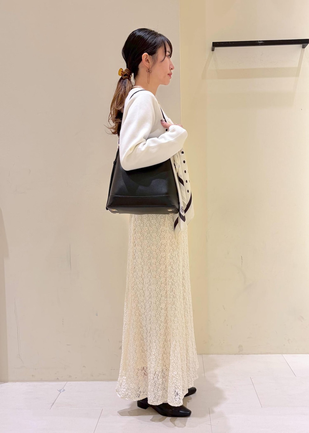 ブラック系のショルダーバッグ、ホワイト系のカーディガン/ボレロ、ホワイト系のスカートを着用したレディースの冬コーディネートの2枚目の写真
