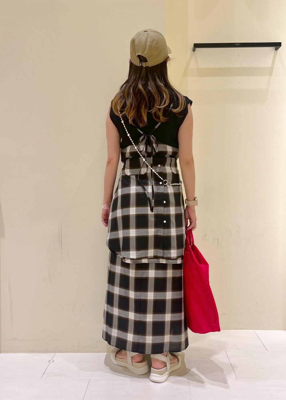 ブラック系のニット/セーター、ホワイト系のサンダル、レッド系のトートバッグを着用したレディースの夏コーディネートの4枚目の写真