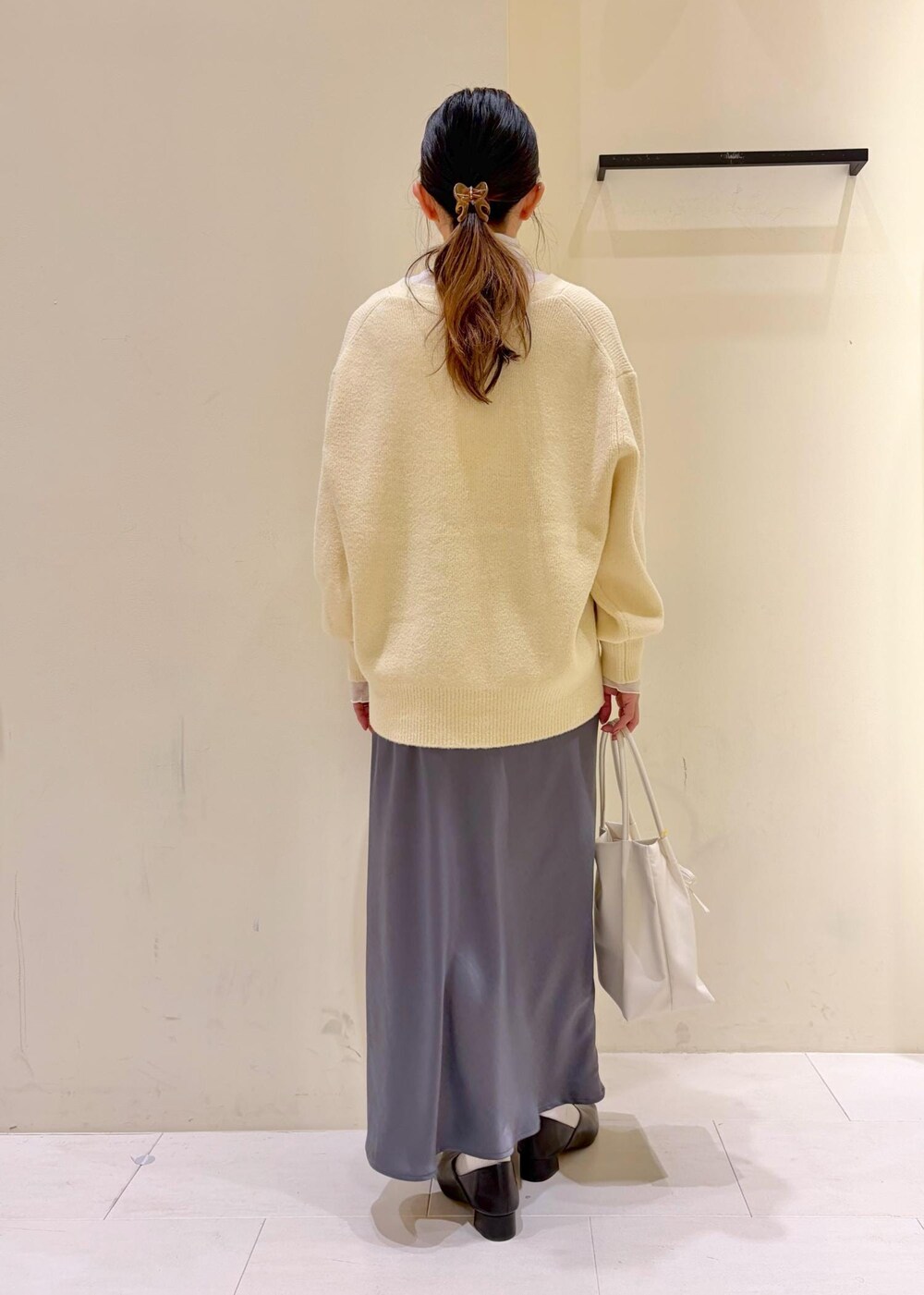 ベージュ系のカーディガン/ボレロ、ホワイト系のトートバッグ、ホワイト系のTシャツ/カットソーを着用したレディースの冬コーディネートの3枚目の写真