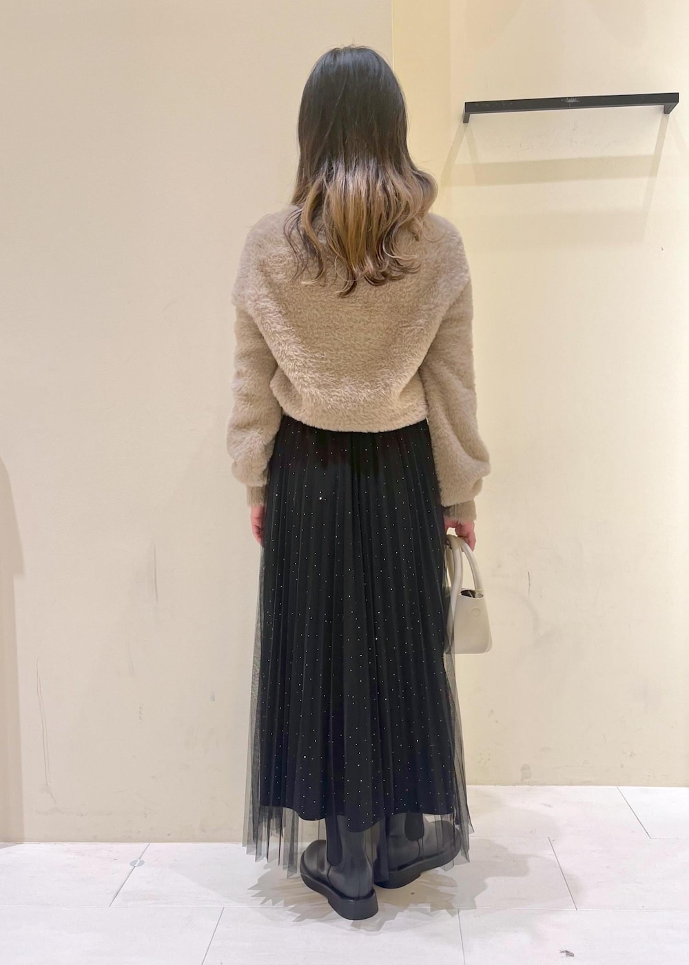 ホワイト系のショルダーバッグ、ブラック系のブーツ、ブラック系のスカートを着用したレディースの冬コーディネートの4枚目の写真