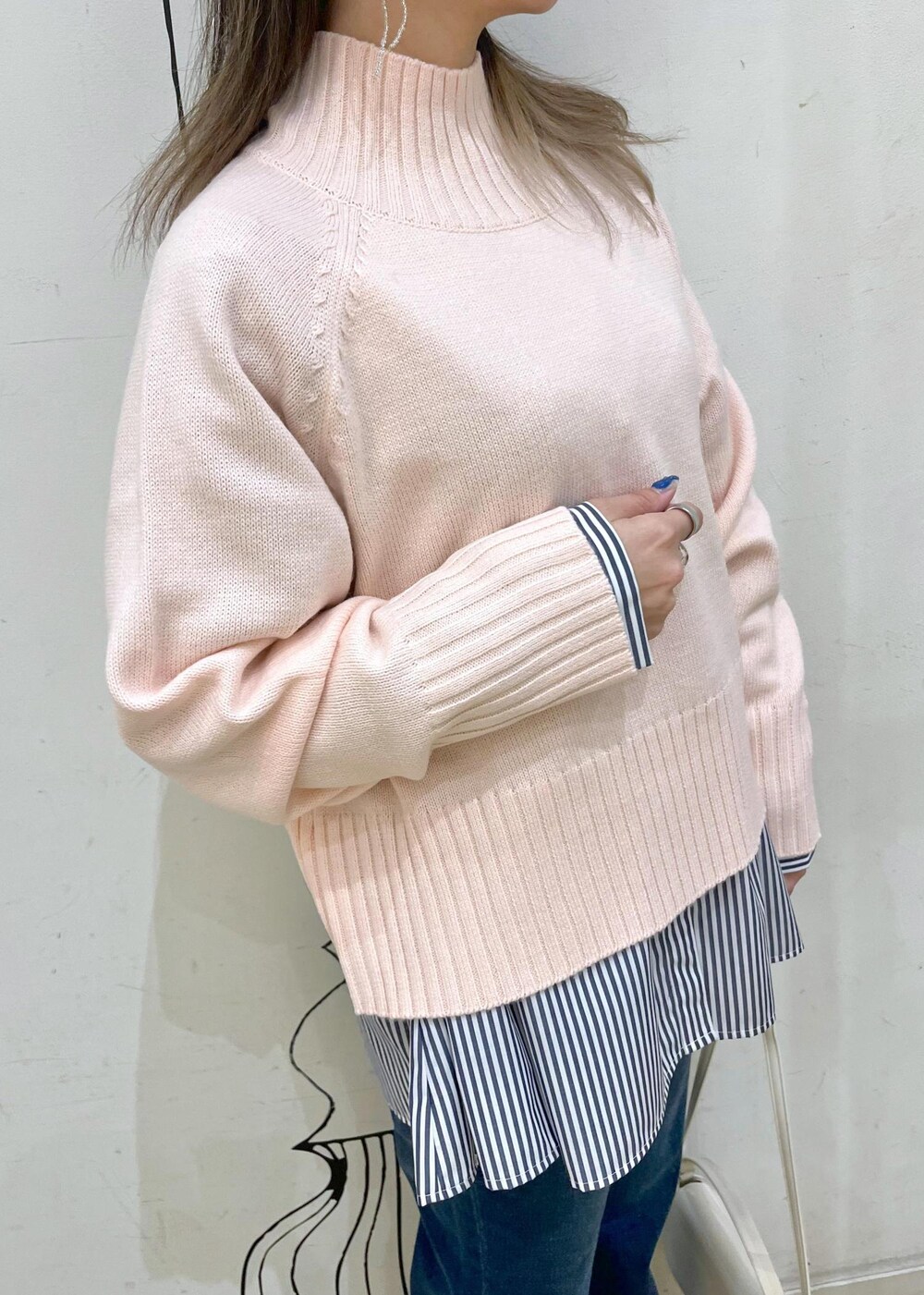 ピンク系のニット/セーター、ホワイト系のハンドバッグ、ブルー系のデニムパンツを着用したレディースの冬コーディネートの4枚目の写真