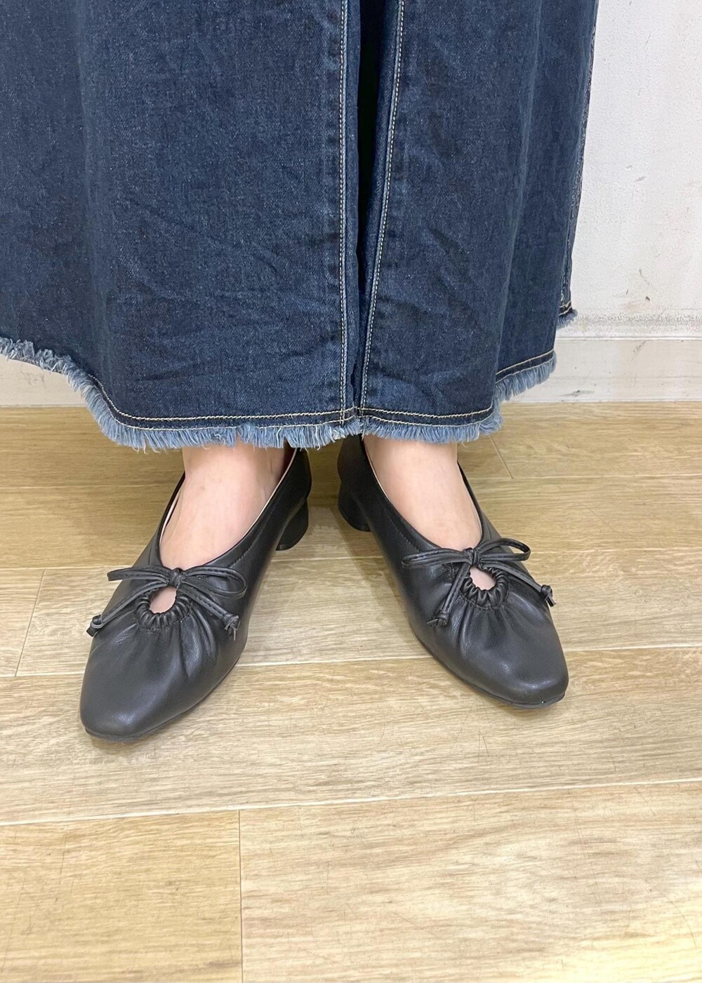 ブラック系のパンプス、ブラック系のトートバッグ、ブルー系のデニムスカートを着用したレディースの秋コーディネートの10枚目の写真