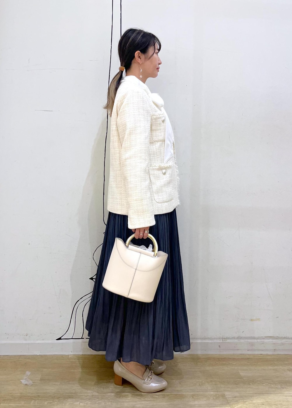 ブルー系のスカート、ベージュ系のローファー、ホワイト系のショルダーバッグを着用したレディースの冬コーディネートの4枚目の写真