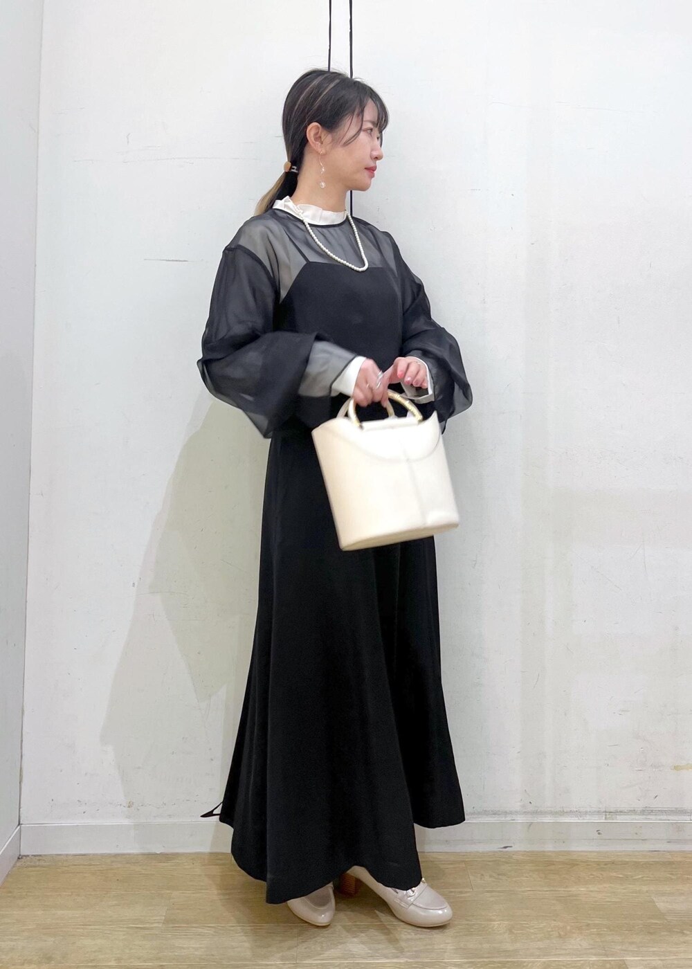 ベージュ系のローファー、ホワイト系のショルダーバッグ、ブラック系のドレスを着用したレディースの冬コーディネートの2枚目の写真