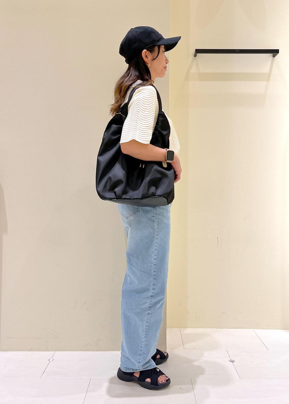 ブルー系のデニムパンツ、ホワイト系のニット/セーター、ブラック系のサンダルを着用したレディースの夏コーディネートの3枚目の写真