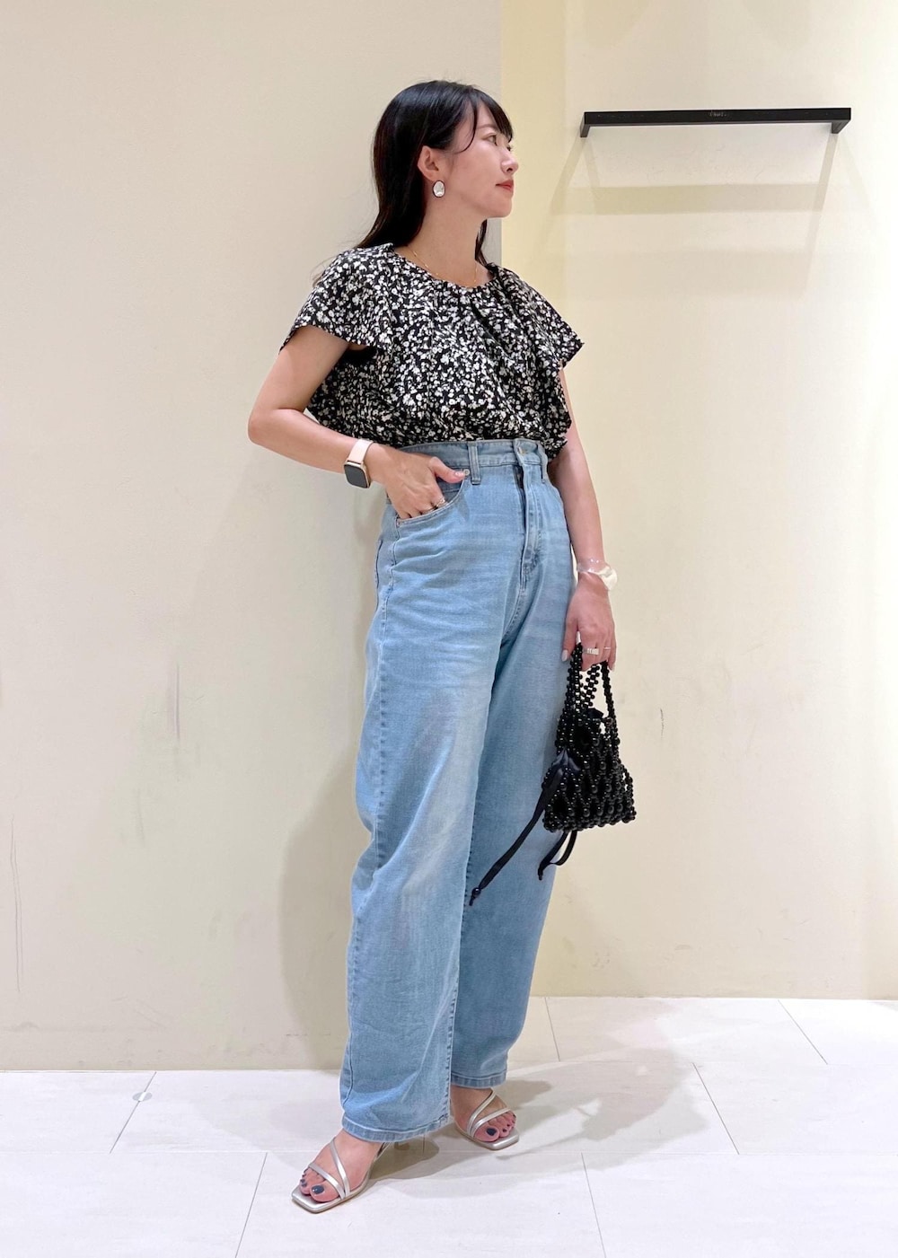 ブルー系のデニムパンツ、ブラック系のハンドバッグ、シルバー系のサンダルを着用したレディースの夏コーディネートの2枚目の写真