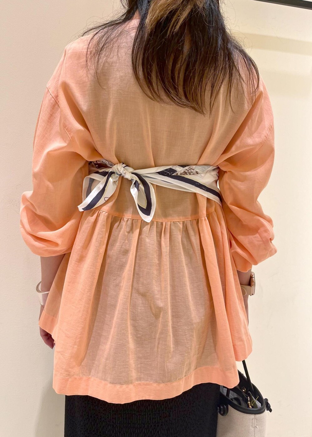 オレンジ系のシャツ/ブラウス、シルバー系のパンプス、ブラック系のトートバッグを着用したレディースの夏コーディネートの7枚目の写真