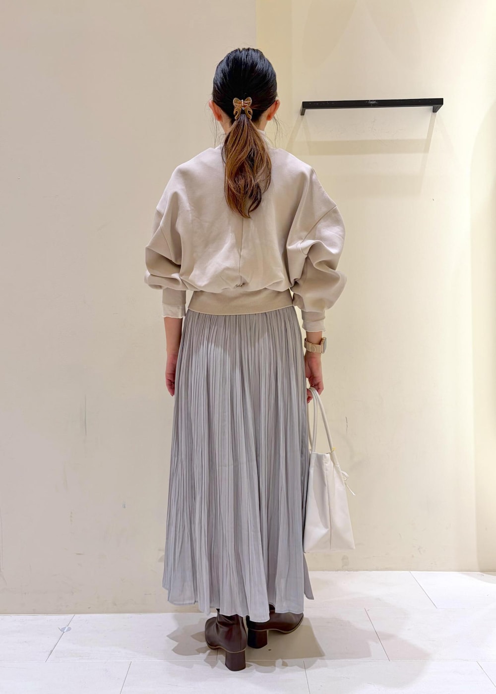 グレー系のスカート、ベージュ系のカーディガン/ボレロ、ホワイト系のトートバッグを着用したレディースの冬コーディネートの3枚目の写真