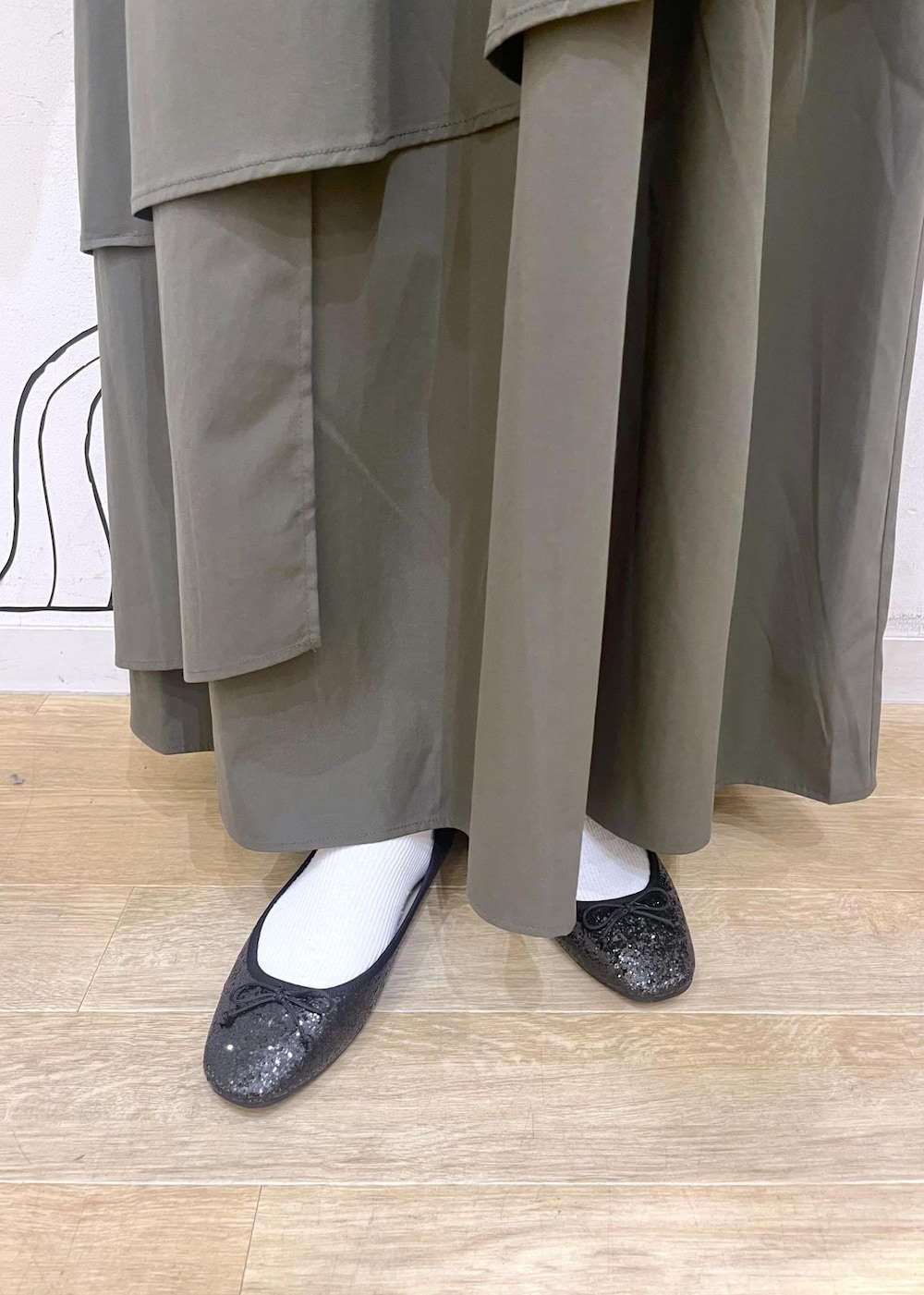 ホワイト系のニット/セーター、ブラック系のバレエシューズ、グリーン系のスカートを着用したレディースの冬コーディネートの9枚目の写真