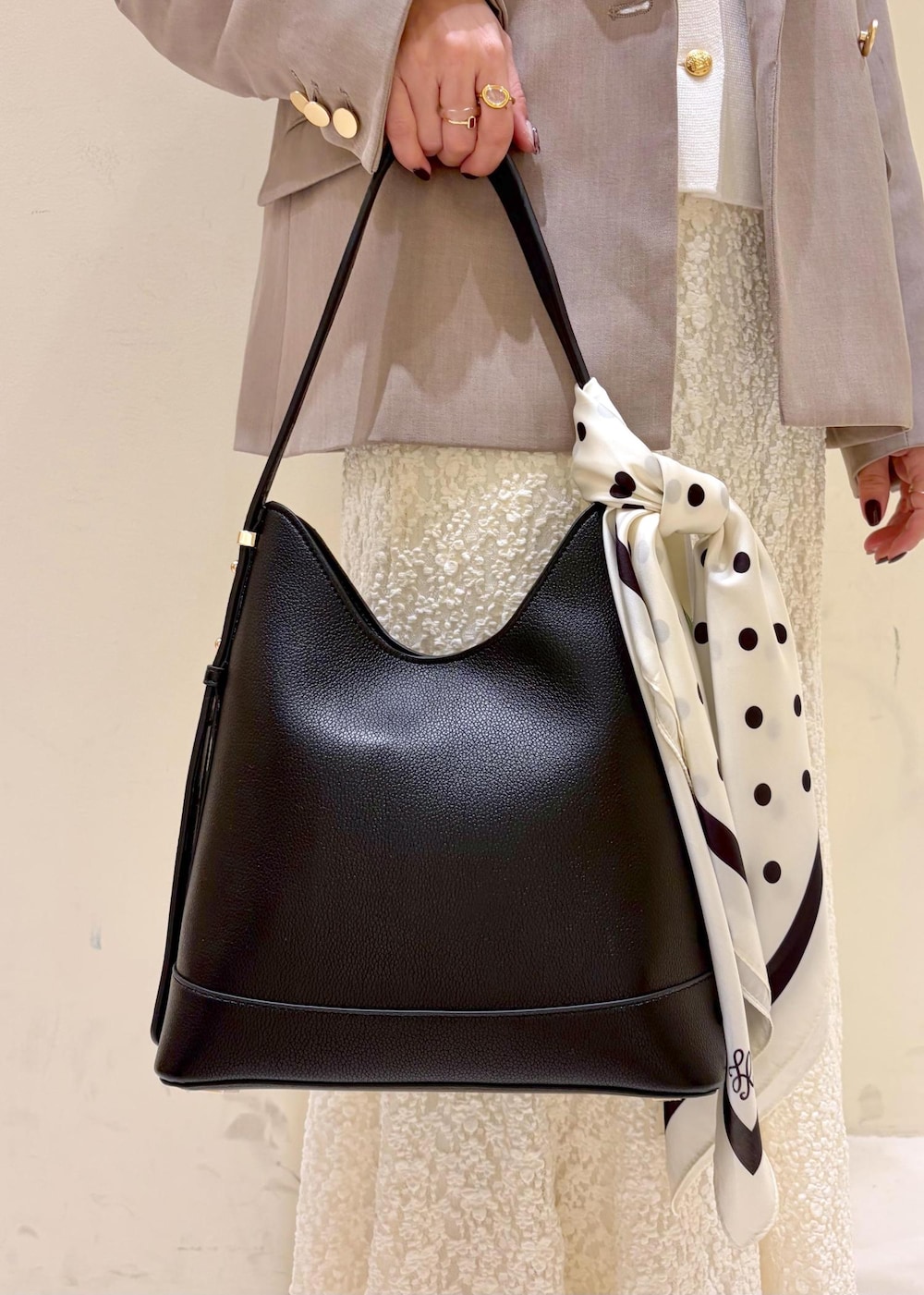 ブラック系のショルダーバッグ、ホワイト系のスカート、ホワイト系のカーディガン/ボレロを着用したレディースの冬コーディネートの7枚目の写真