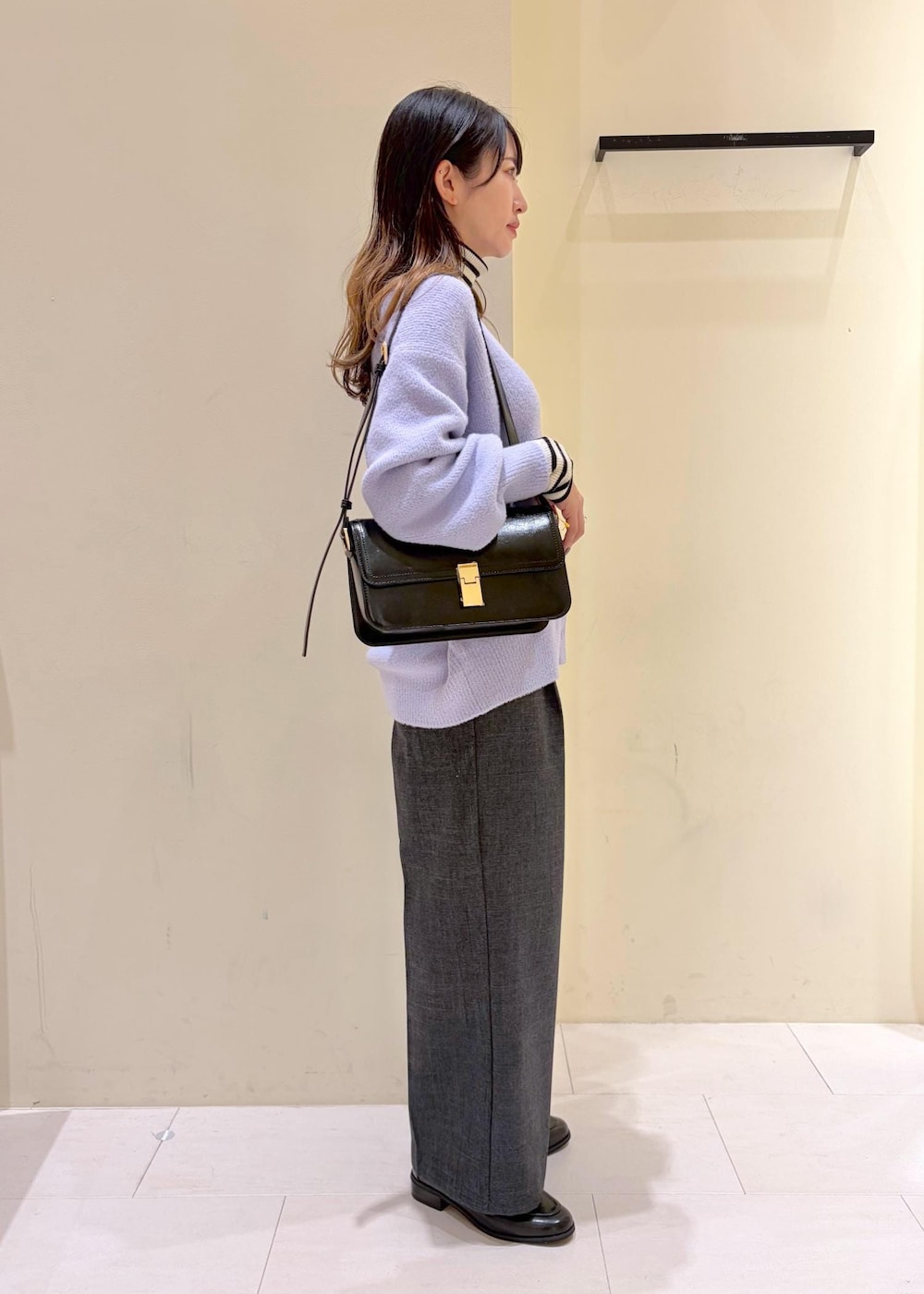 ブラック系のショルダーバッグ、ホワイト系のニット/セーター、グレー系のスラックスを着用したレディースの冬コーディネートの3枚目の写真