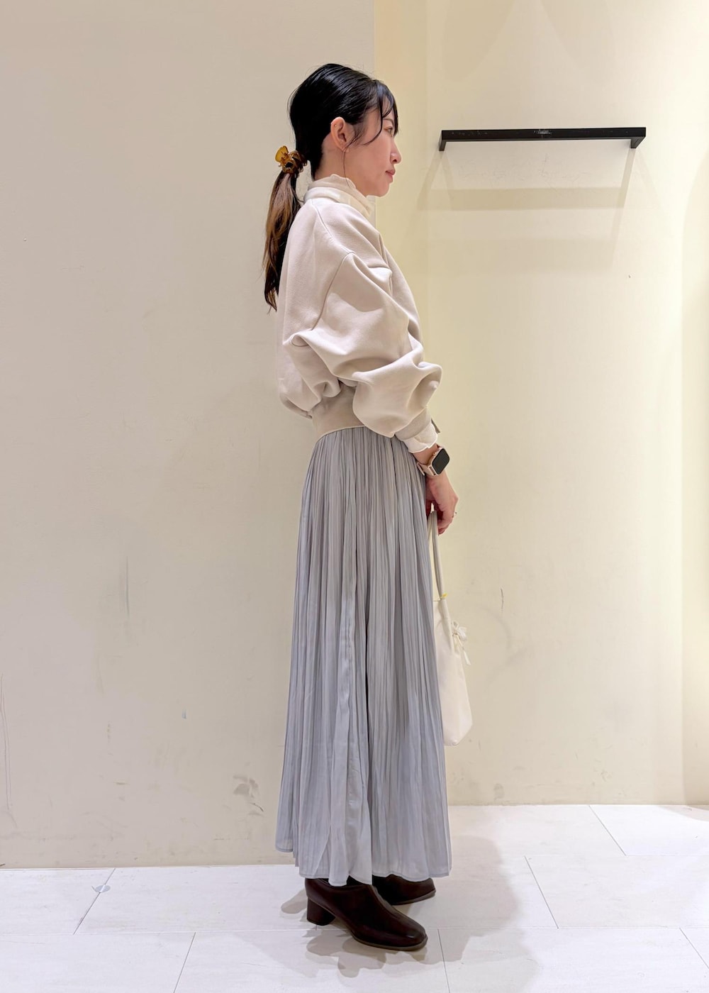 グレー系のスカート、ベージュ系のカーディガン/ボレロ、ホワイト系のトートバッグを着用したレディースの冬コーディネートの2枚目の写真