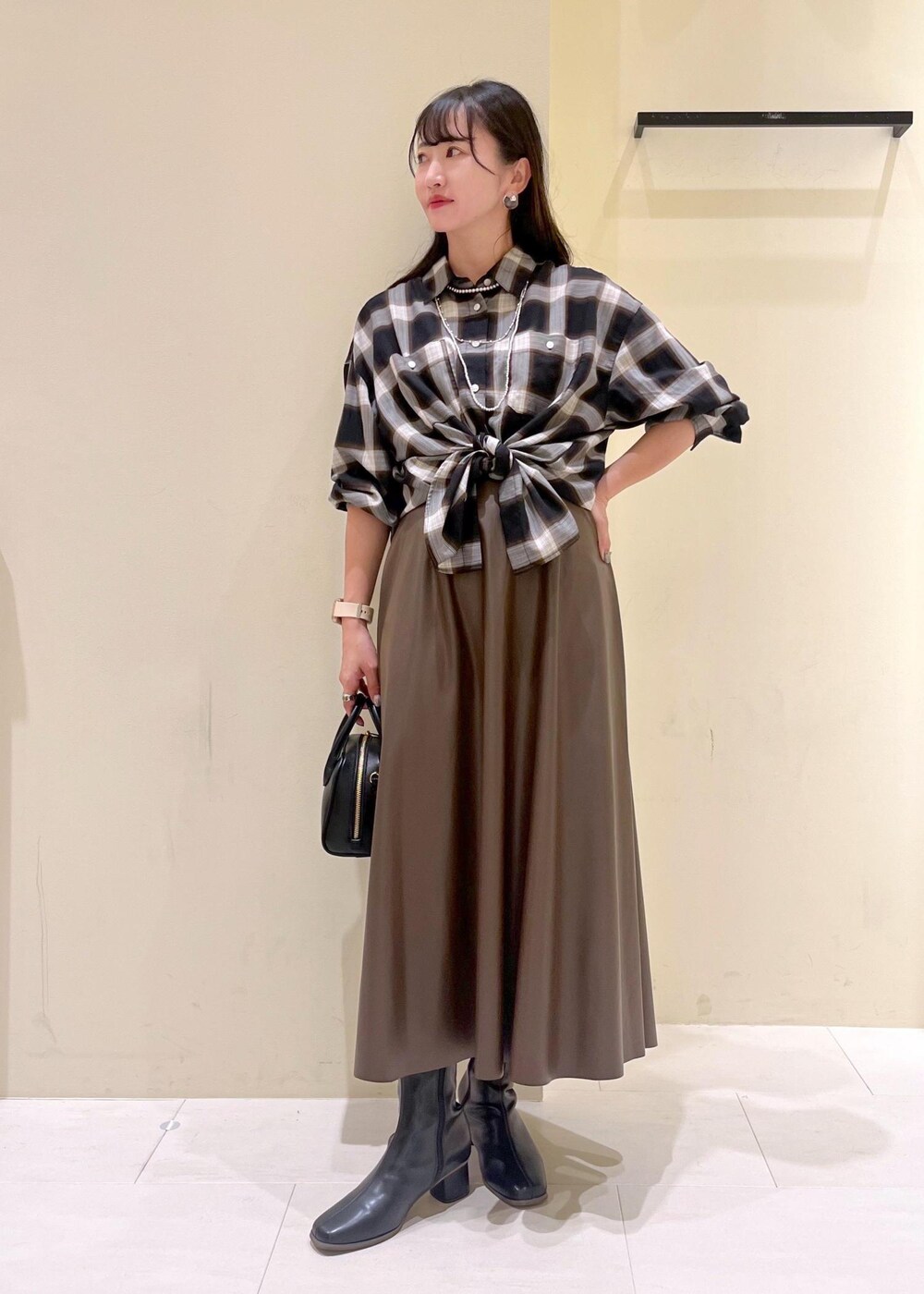 ブラック系のシャツ/ブラウス、グリーン系のスカート、ブラック系のブーツを着用したレディースの秋コーディネートの2枚目の写真