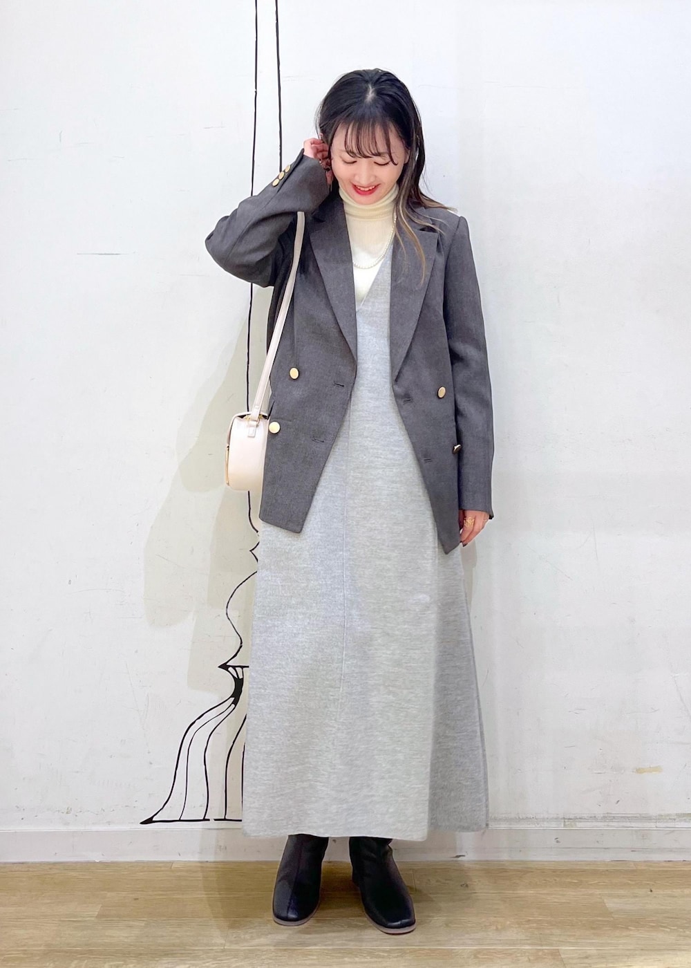 ホワイト系のショルダーバッグ、ブラック系のブーツ、ホワイト系のニット/セーターを着用したレディースの冬コーディネートの3枚目の写真