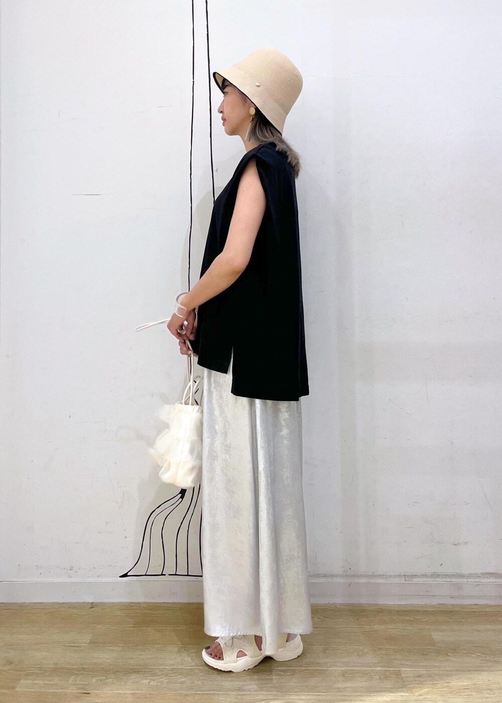 シルバー系のスカート、ブラック系のTシャツ/カットソー、ホワイト系のサンダルを着用したレディースの夏コーディネートの3枚目の写真