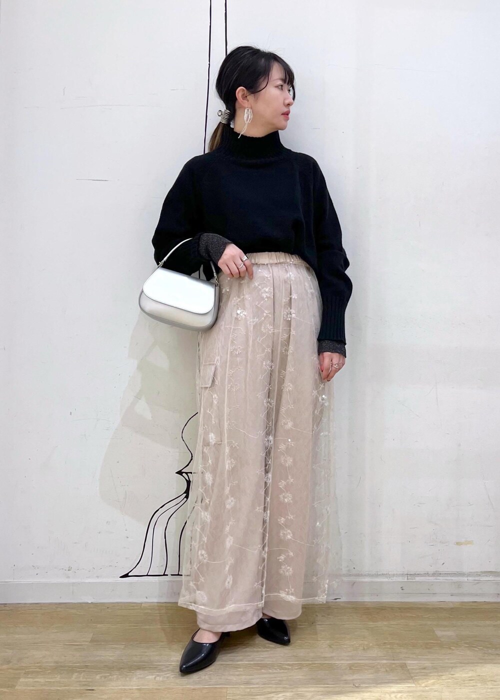 ブラック系のニット/セーター、ホワイト系のスカート、ブラック系のパンプスを着用したレディースの冬コーディネートの2枚目の写真