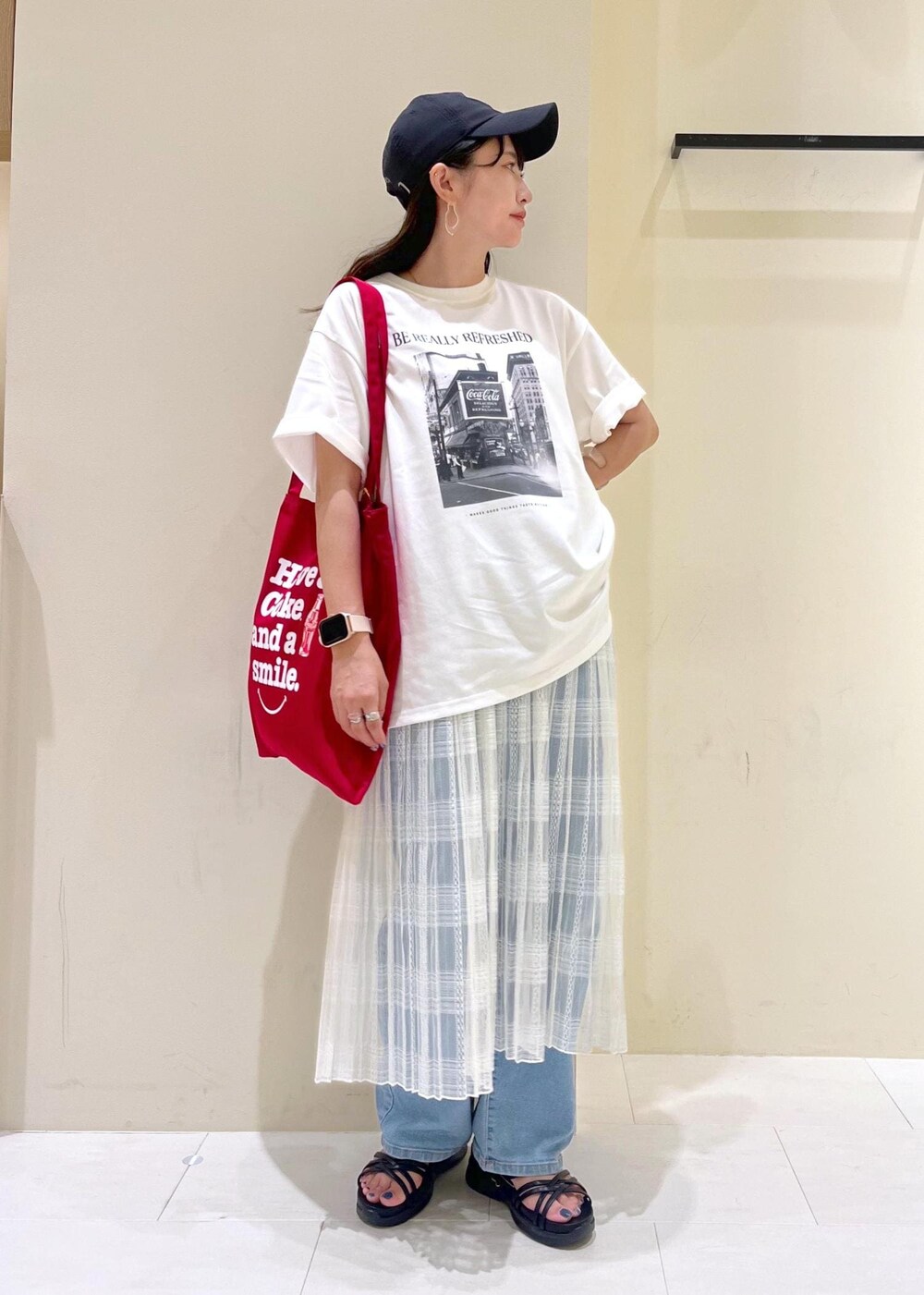 ブルー系のデニムパンツ、ホワイト系のスカート、ブラック系のサンダルを着用したレディースの夏コーディネートの2枚目の写真