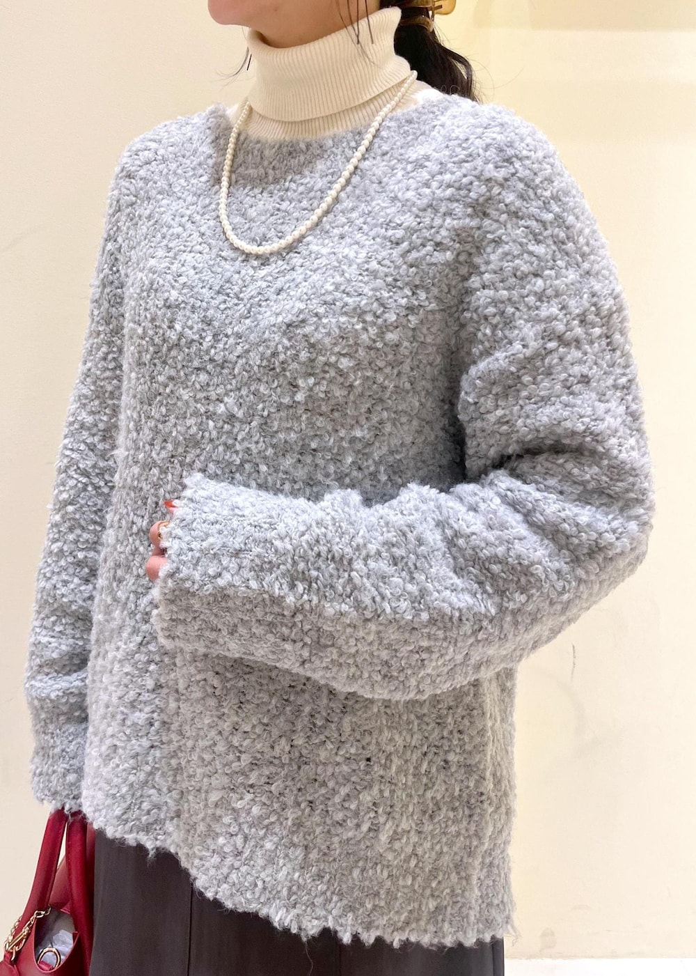 ホワイト系のニット/セーター、グレー系のスカート、レッド系のショルダーバッグを着用したレディースの冬コーディネートの6枚目の写真