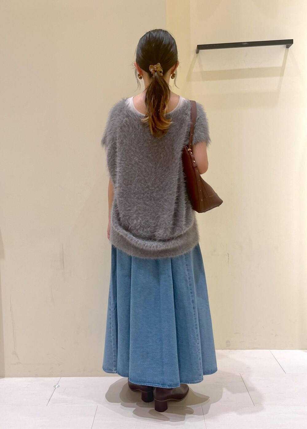 グレー系のタンクトップ、ブルー系のスカート、グレー系のベストを着用したレディースの秋コーディネートの4枚目の写真