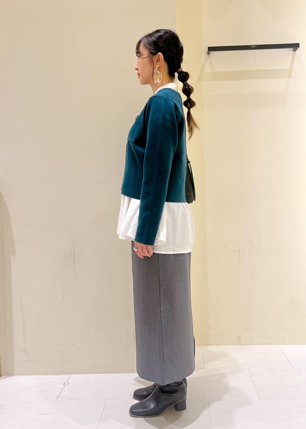 グレー系のスカート、ホワイト系のシャツ/ブラウス、グリーン系のカーディガン/ボレロを着用したレディースの秋コーディネートの4枚目の写真