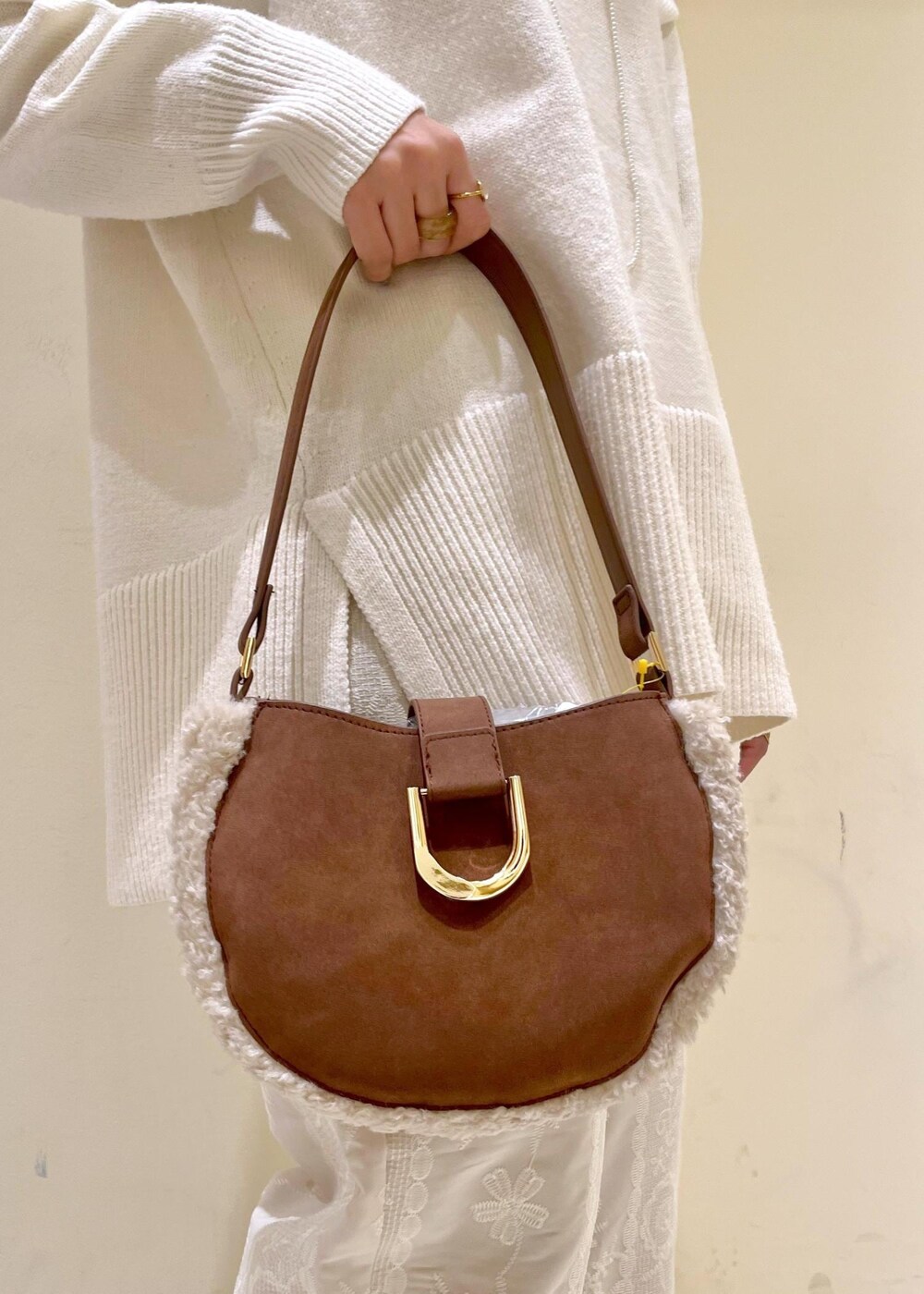 ホワイト系のニット/セーター、ブラウン系のショルダーバッグ、ブラウン系のローファーを着用したレディースの冬コーディネートの10枚目の写真