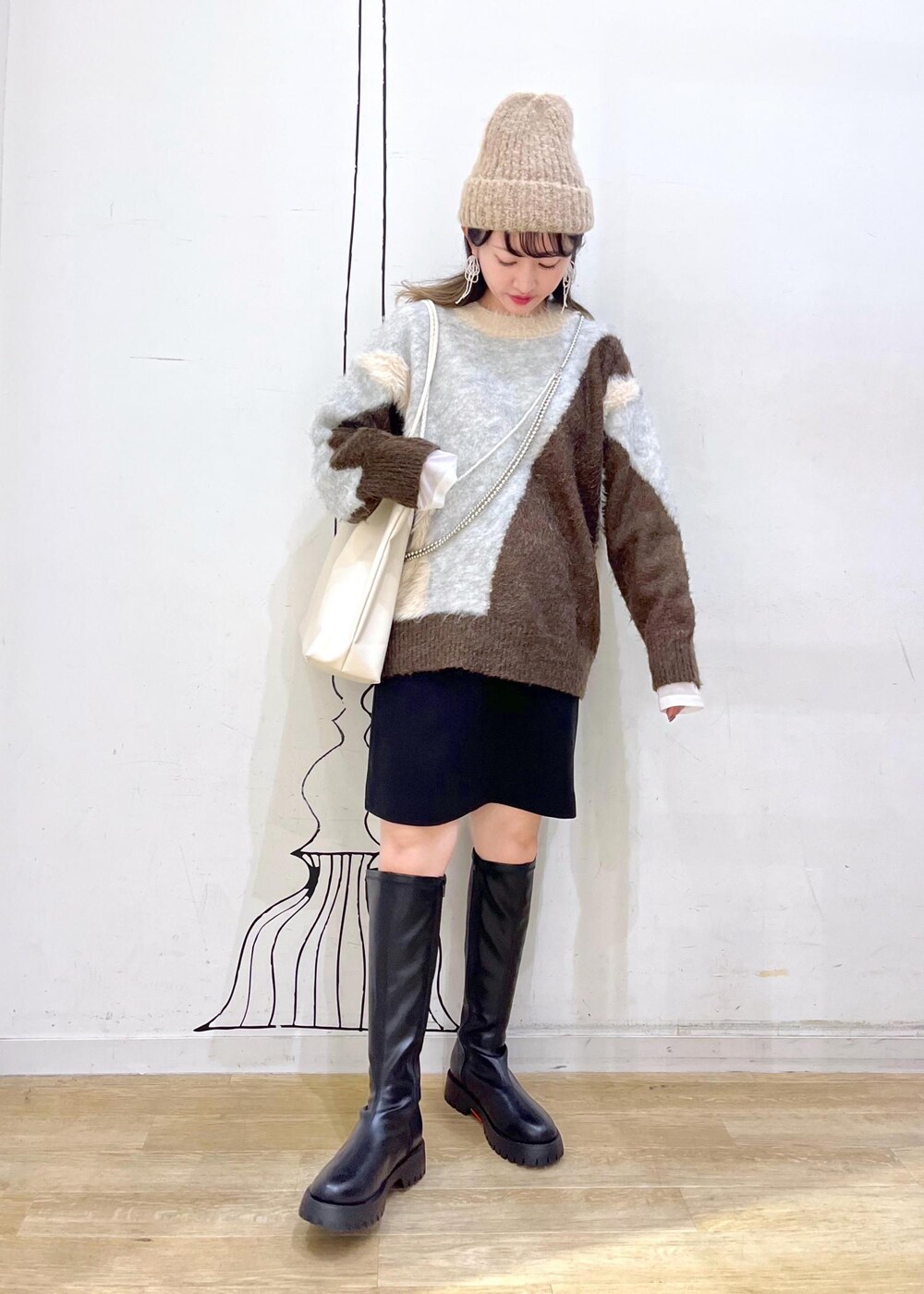 ブラック系のスカート、ブラック系のブーツ、ブラウン系のニット/セーターを着用したレディースの秋コーディネートの2枚目の写真