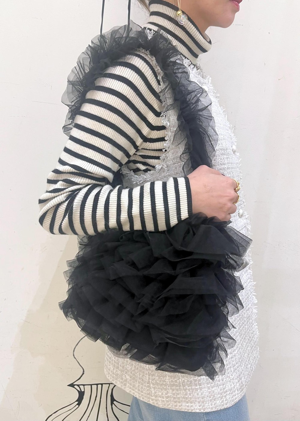 ホワイト系のニット/セーター、ブルー系のデニムパンツ、ブラック系のレインシューズを着用したレディースの冬コーディネートの7枚目の写真