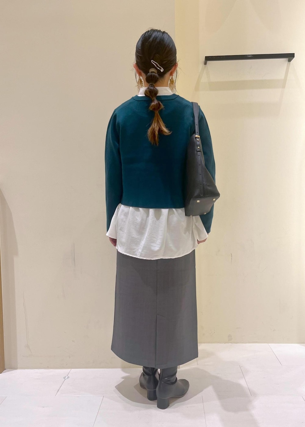 グレー系のスカート、ホワイト系のシャツ/ブラウス、グリーン系のカーディガン/ボレロを着用したレディースの秋コーディネートの3枚目の写真